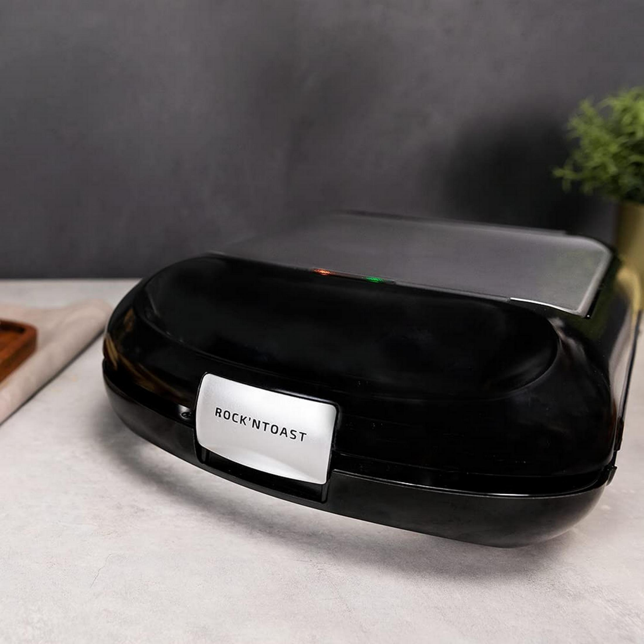 Black toaster with silver handle and indicator lights on a table.