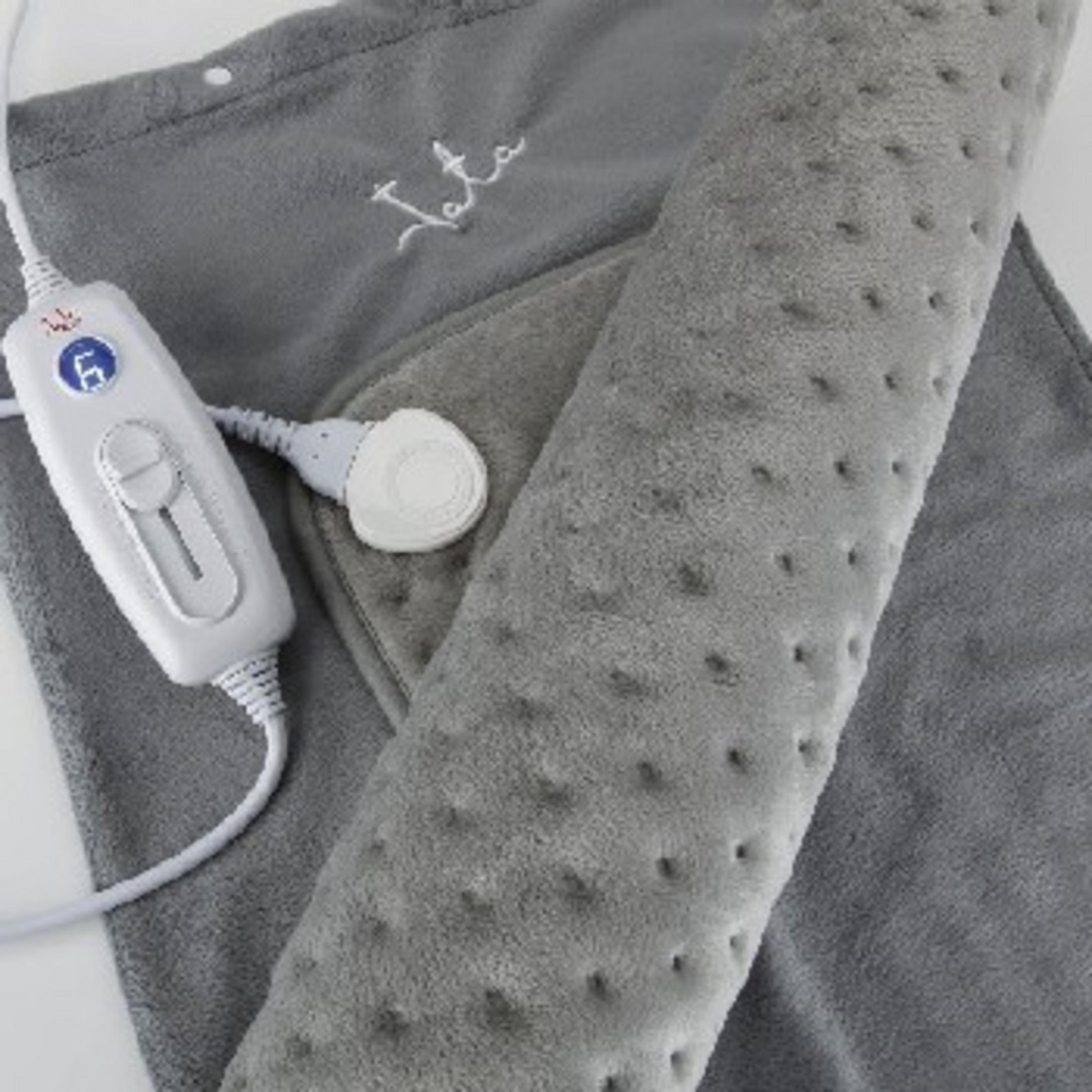 Manta eléctrica gris con mando blanco y cable, enrollada.