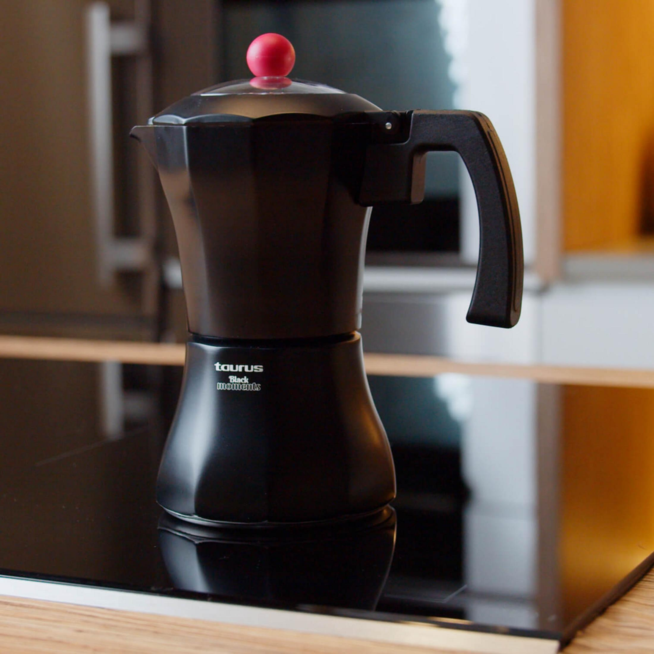 Caffettiera nera con pomello rosso su un piano cottura.