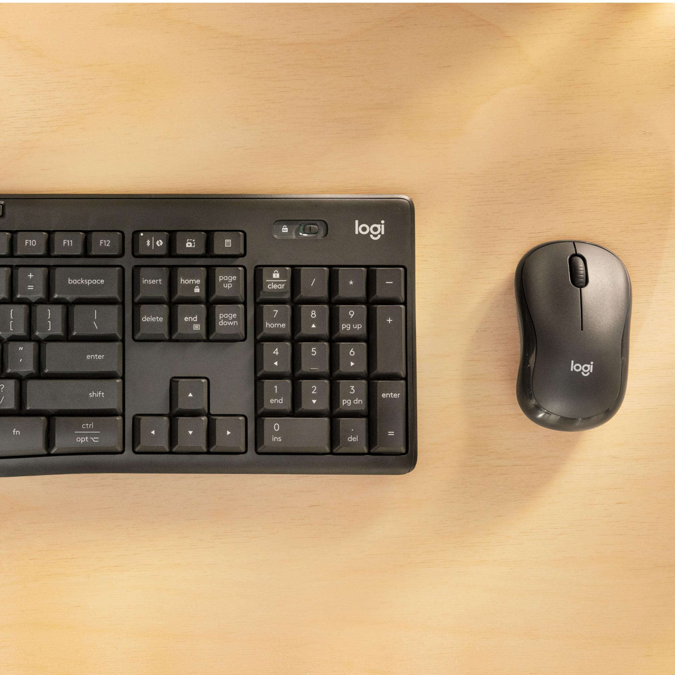 Tastiera e mouse Logitech neri su superficie in legno chiaro.