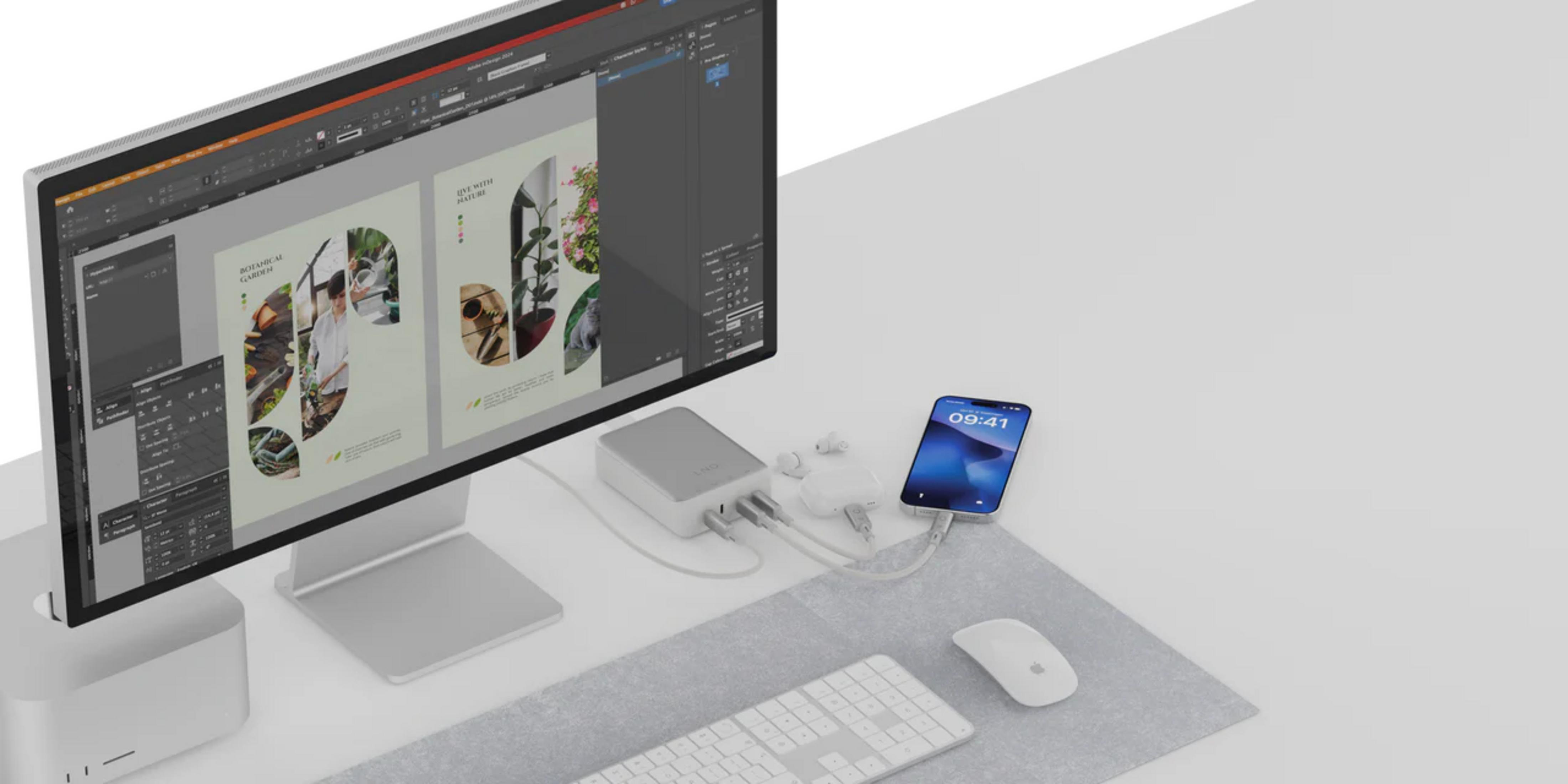 Un monitor del computer mostra software di progettazione. Telefono, hub, tastiera, mouse e auricolari sulla scrivania.