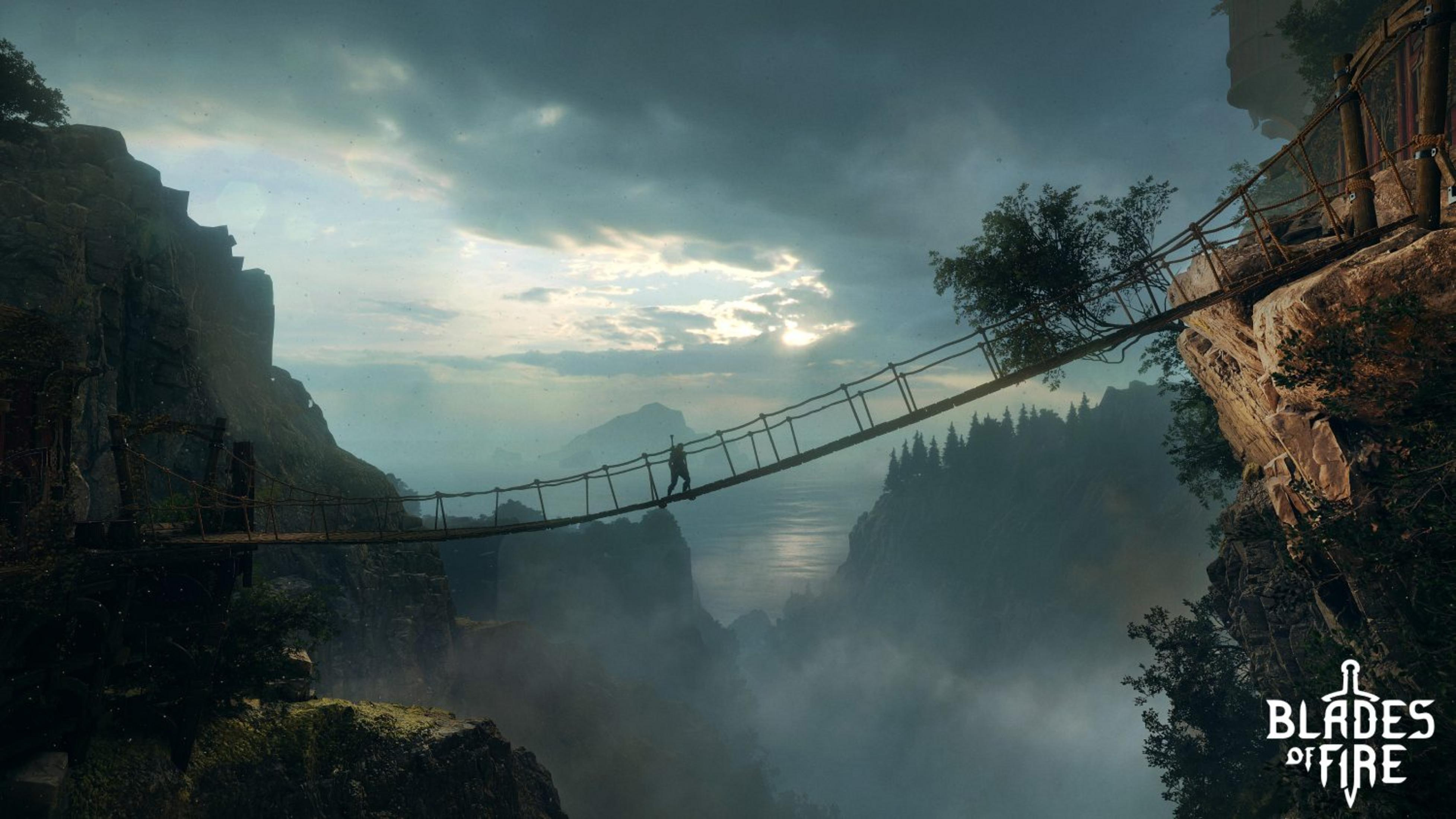 Una persona attraversa un ponte di corda sopra un canyon nebbioso al tramonto.