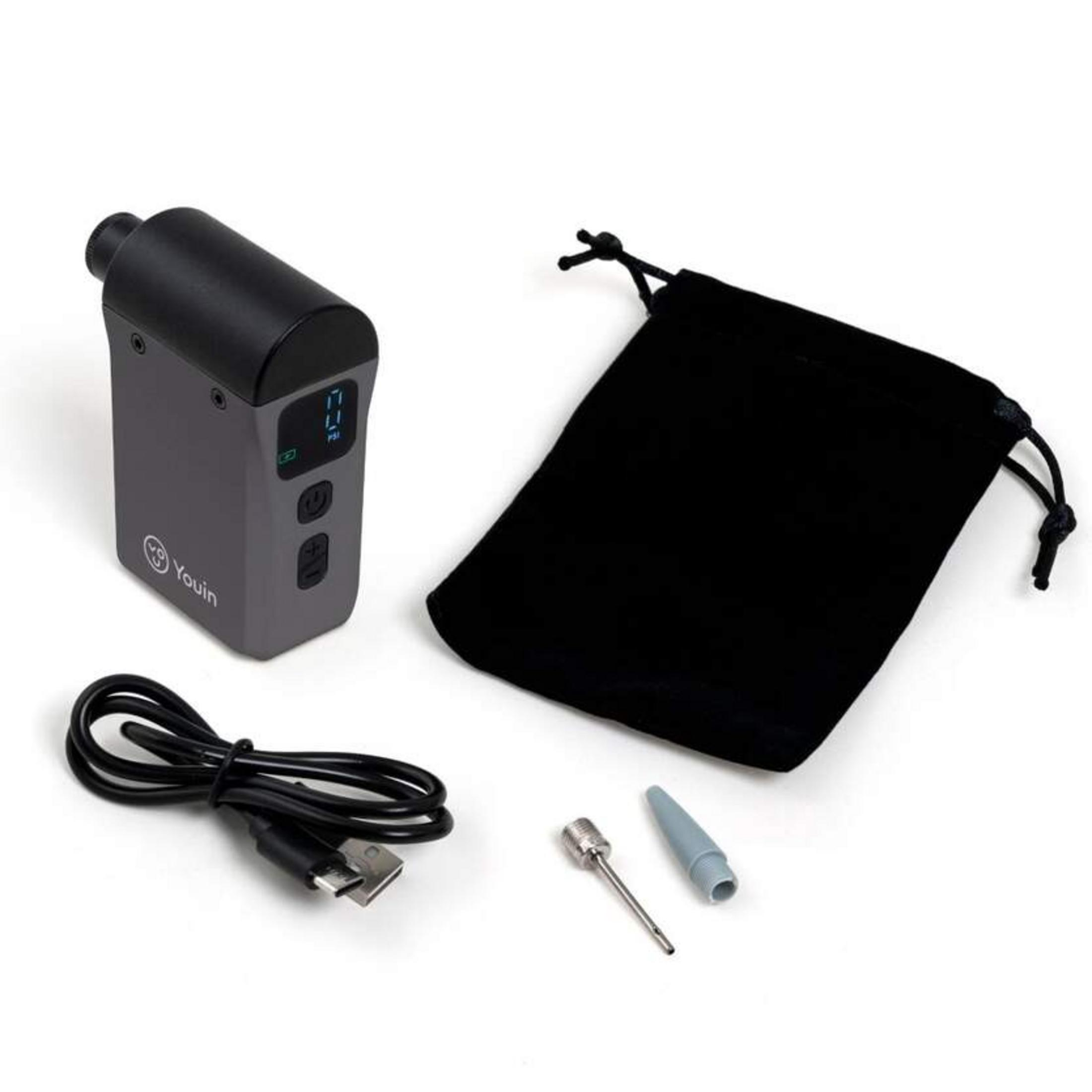 Bomba de aire portátil gris con cable USB, bolsa negra y dos boquillas sobre fondo blanco.