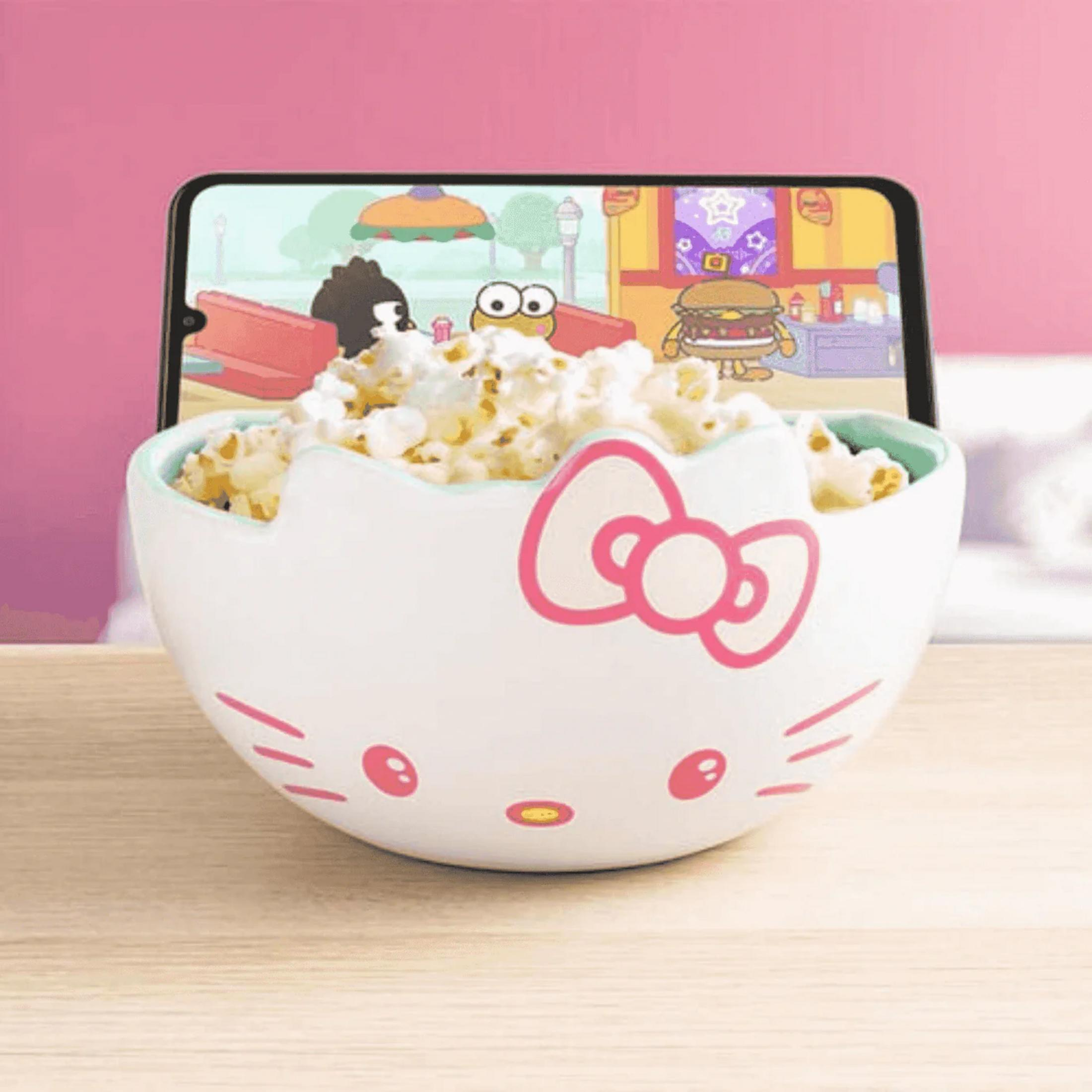 Ein Hello Kitty-Napf gefüllt mit Popcorn vor einem Smartphone, das einen Cartoon zeigt.
