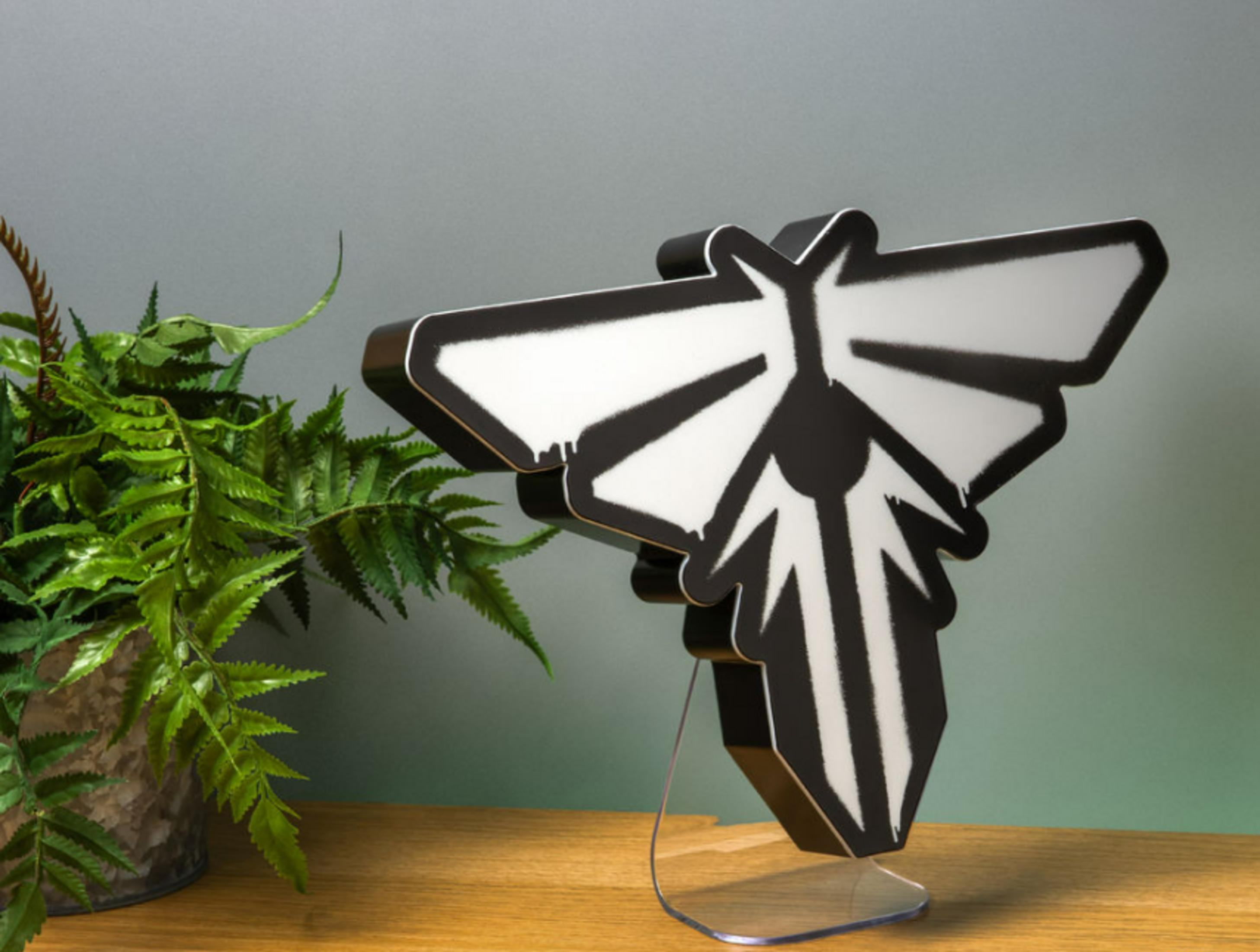 Una pieza de exhibición de luciérnaga en blanco y negro junto a una planta de helecho verde.