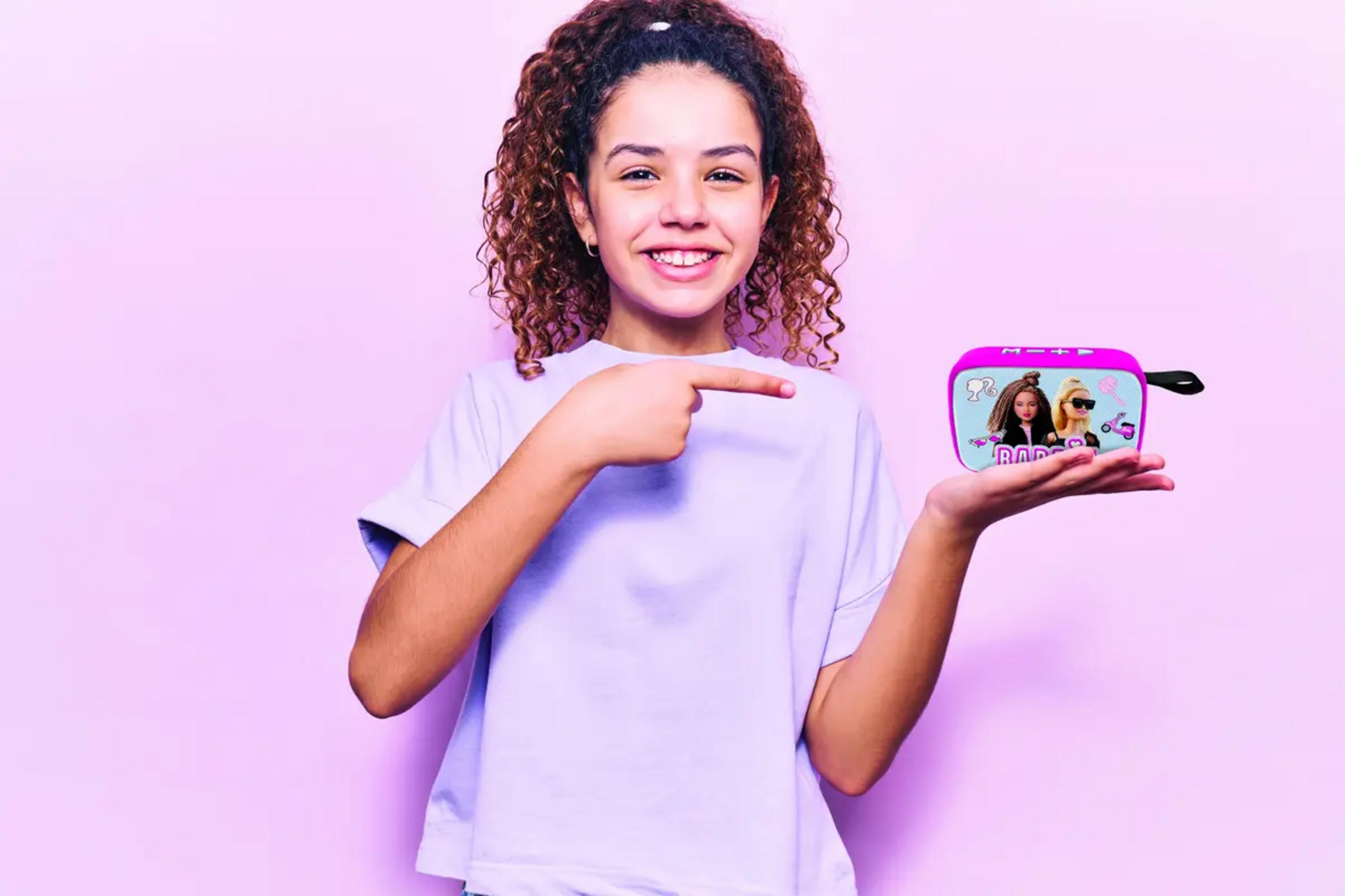 Una ragazza con i capelli ricci indica una scatola Barbie rosa.