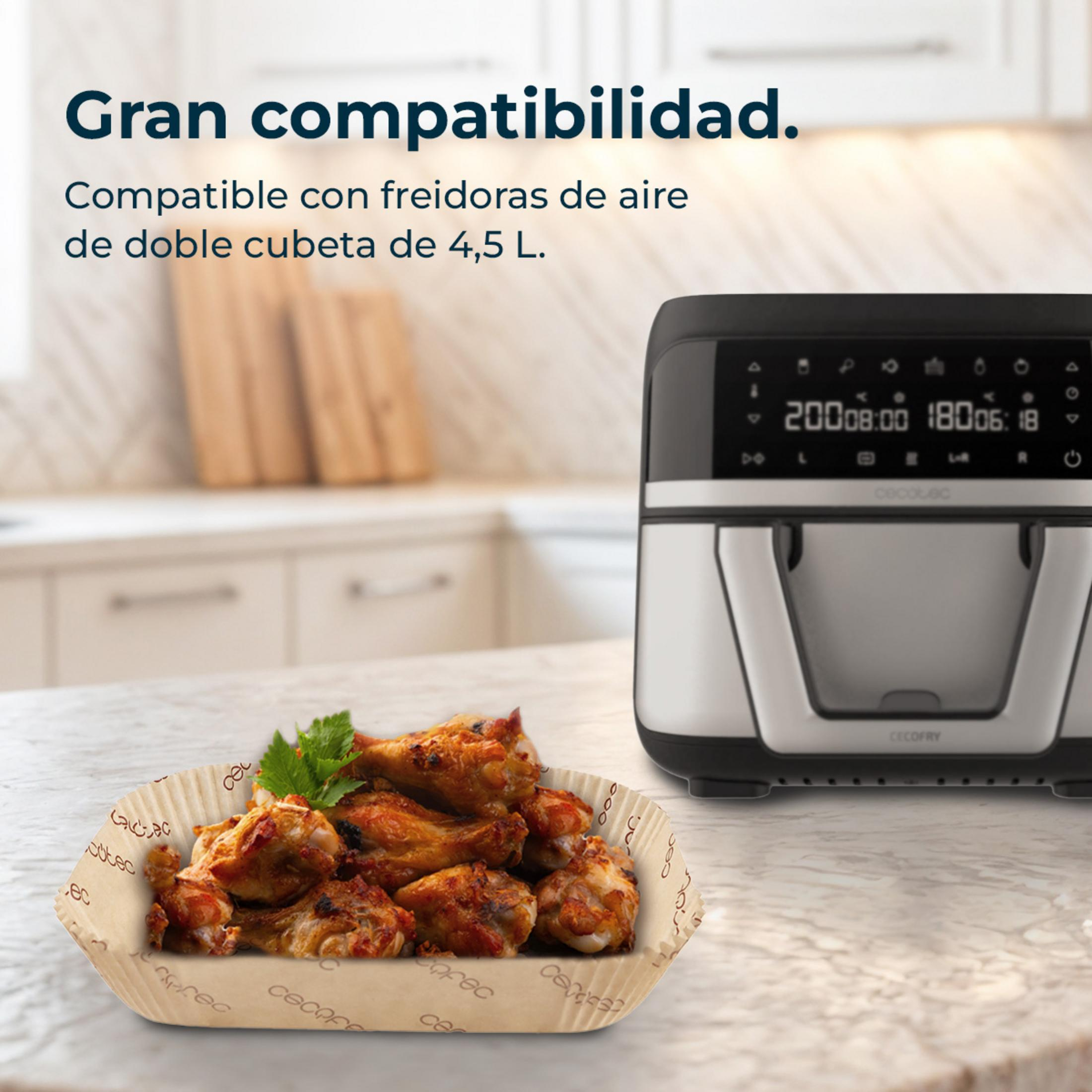 Una freidora de aire plateada junto a un plato de alitas de pollo. Fondo de cocina.