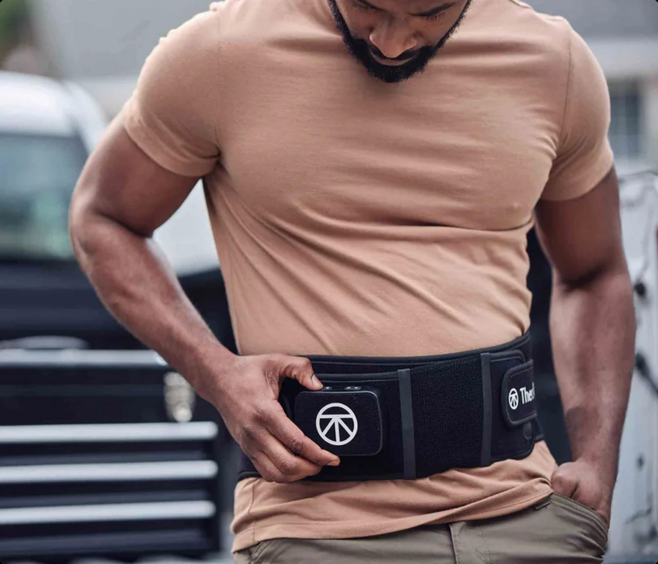 Un hombre con barba lleva una camiseta beige y una riñonera negra con un símbolo blanco.
