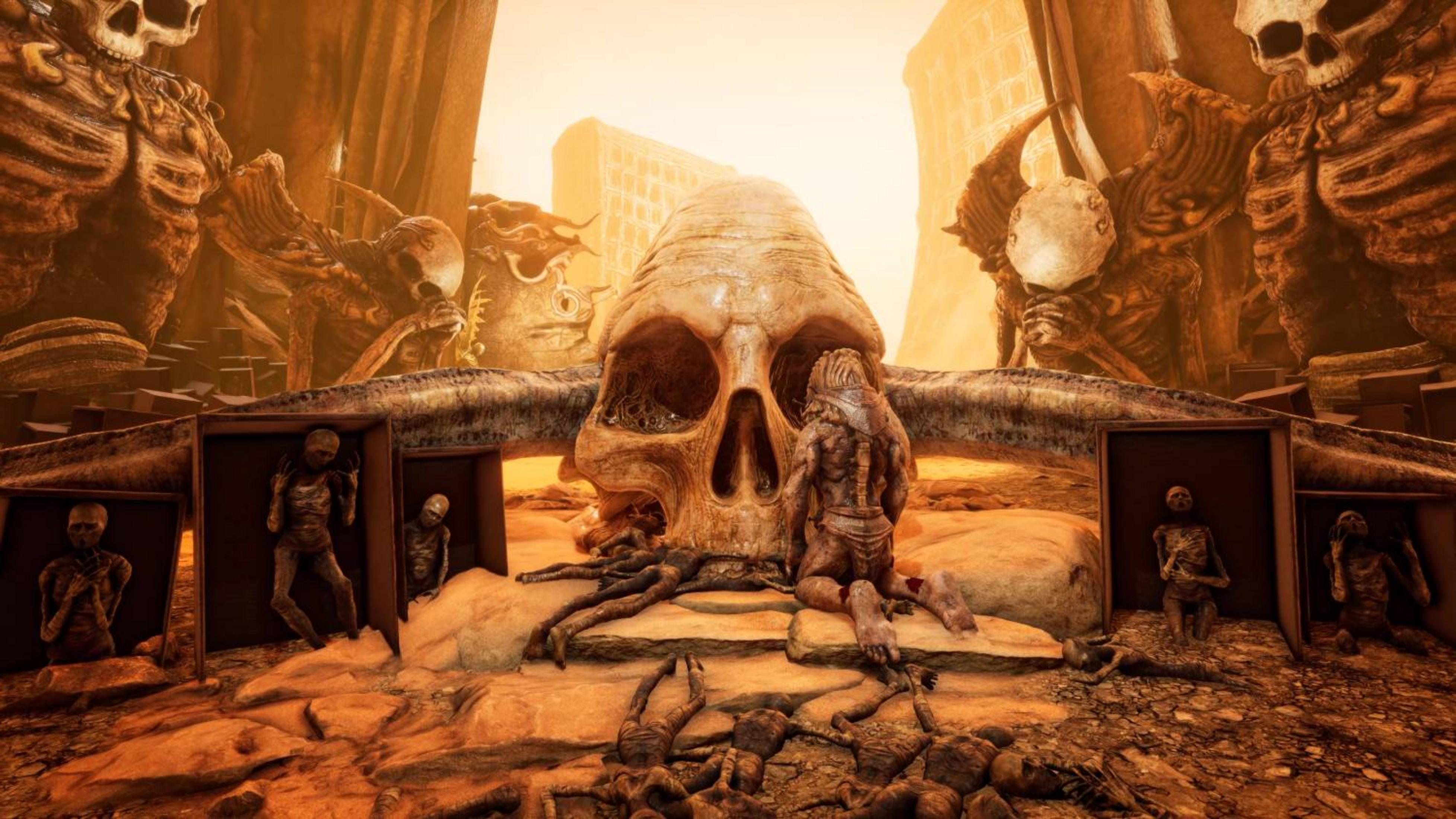 Creature scheletriche e una scultura di teschio gigante in un paesaggio polveroso e apocalittico.