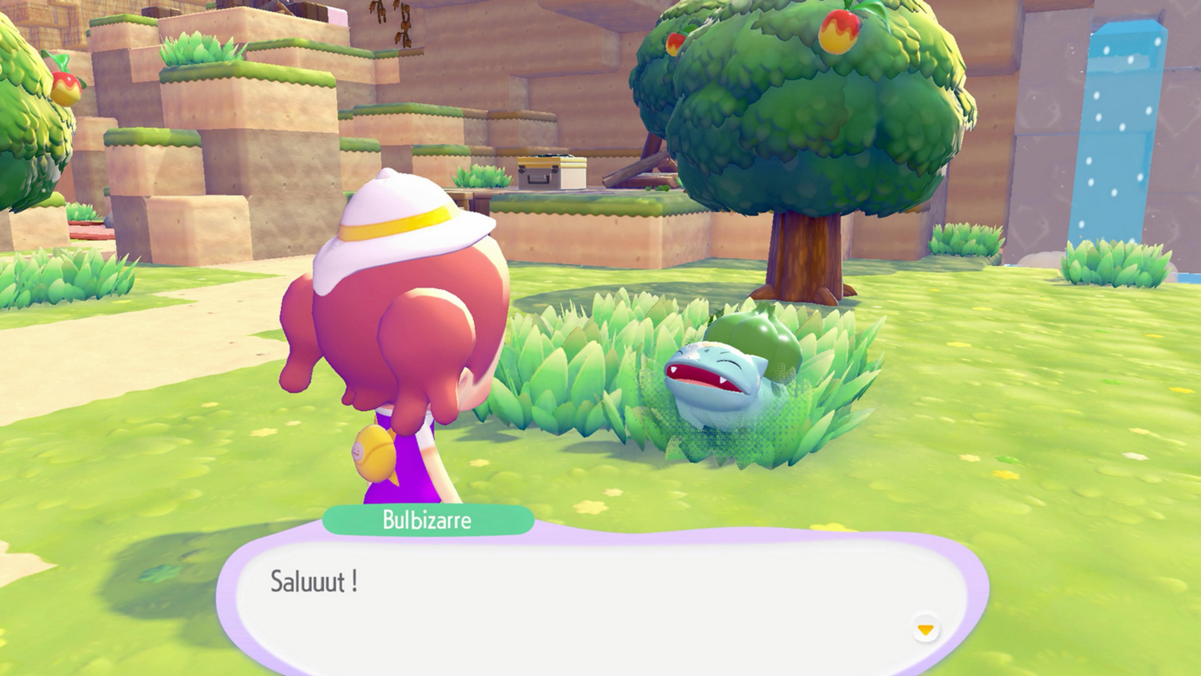Un personaggio con cappello sta davanti a un albero e un Bulbasaur nell'erba.