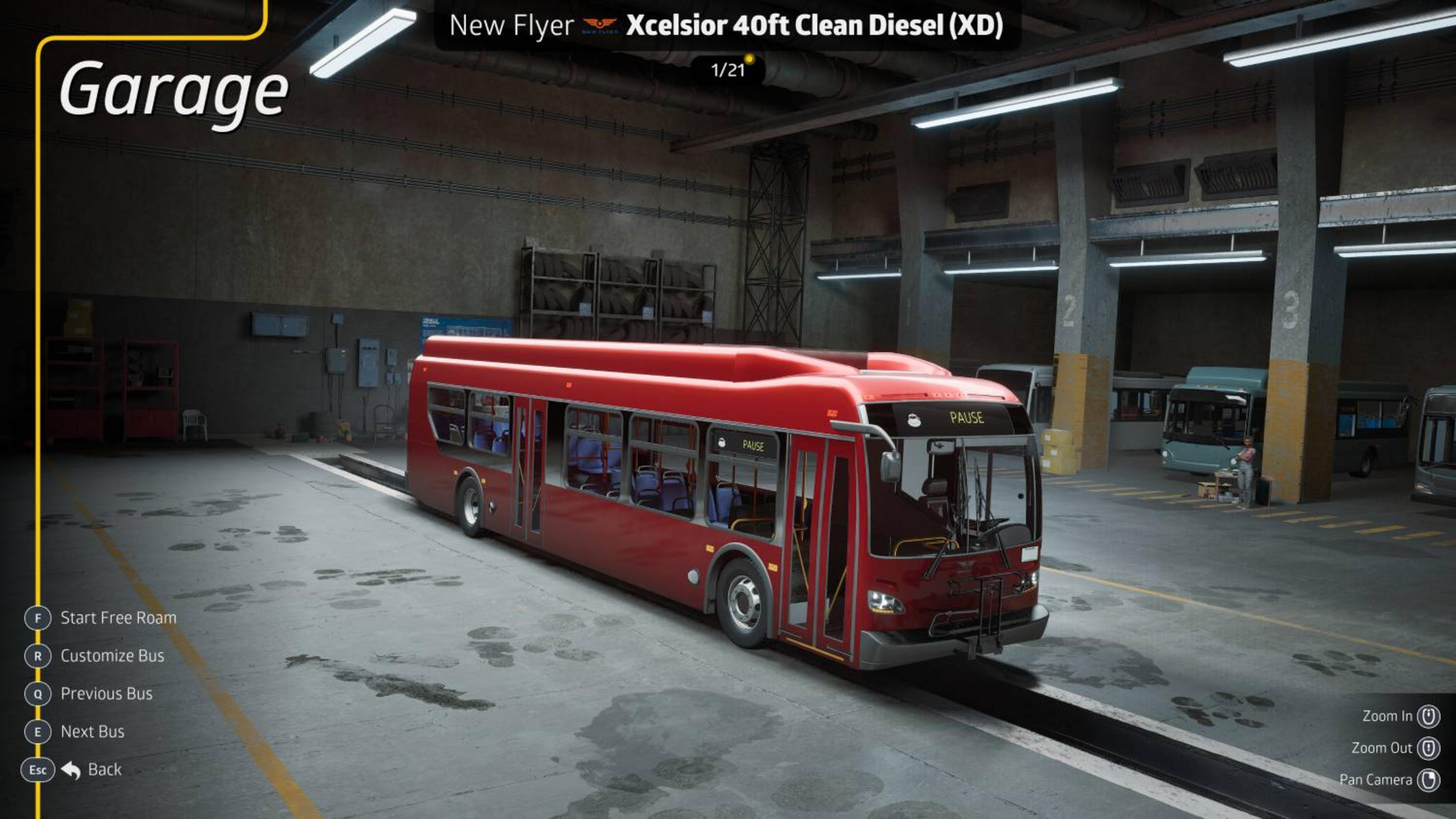 Un autobus rosso è parcheggiato in un garage con altri autobus sullo sfondo.