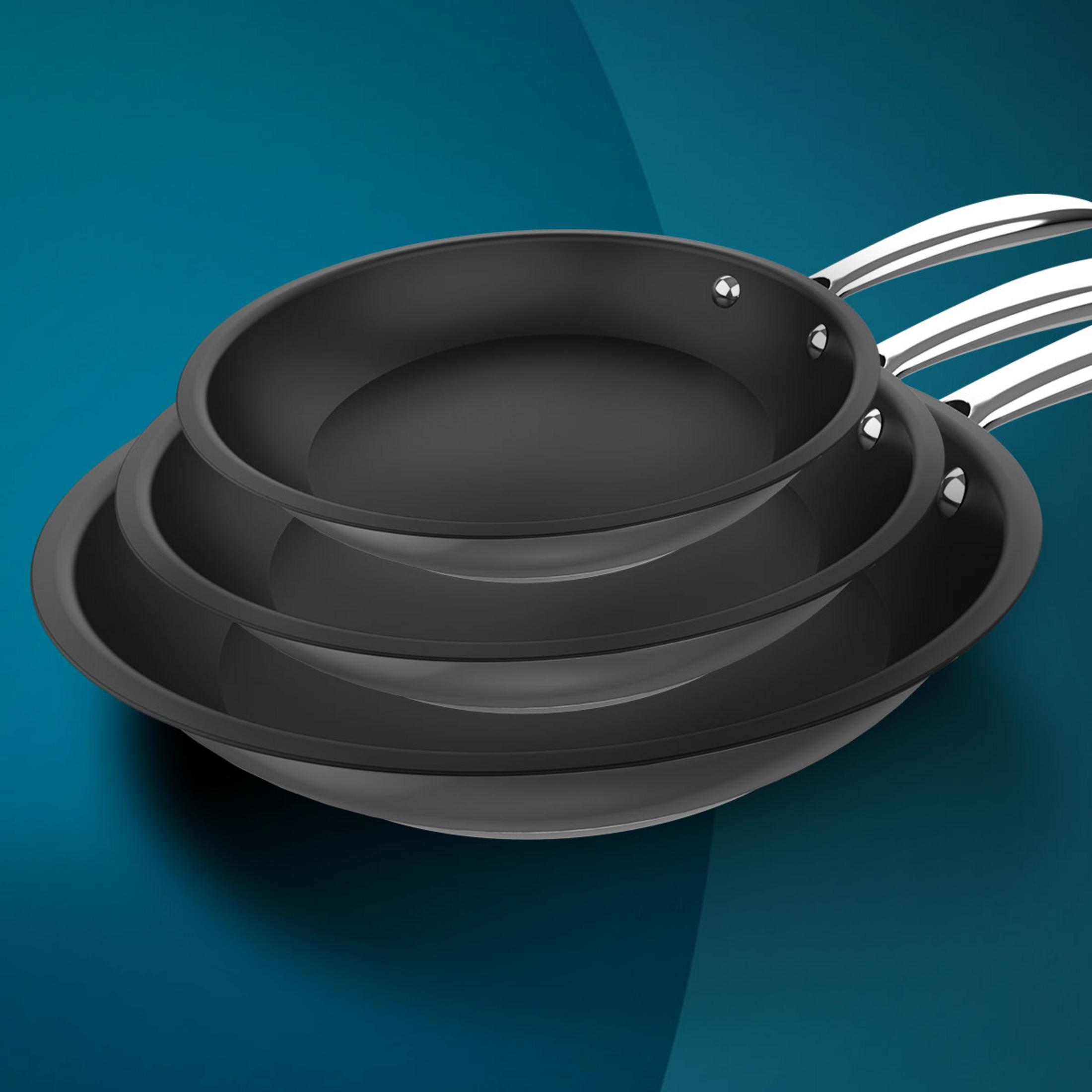 Three black frying pans stacked on a blue background. Shiny handles are visible.