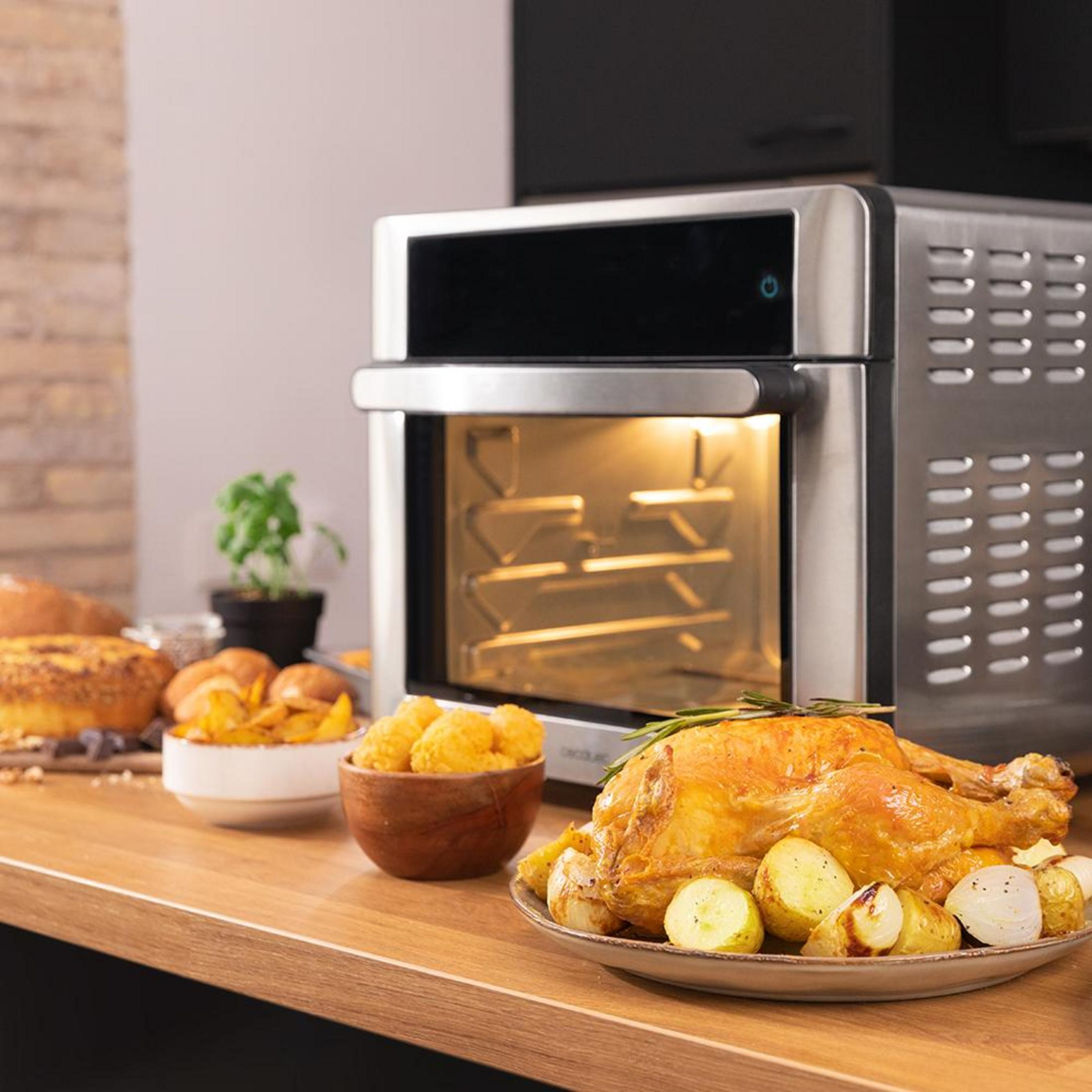 Un pollo arrosto con patate e cipolle accanto a un forno.