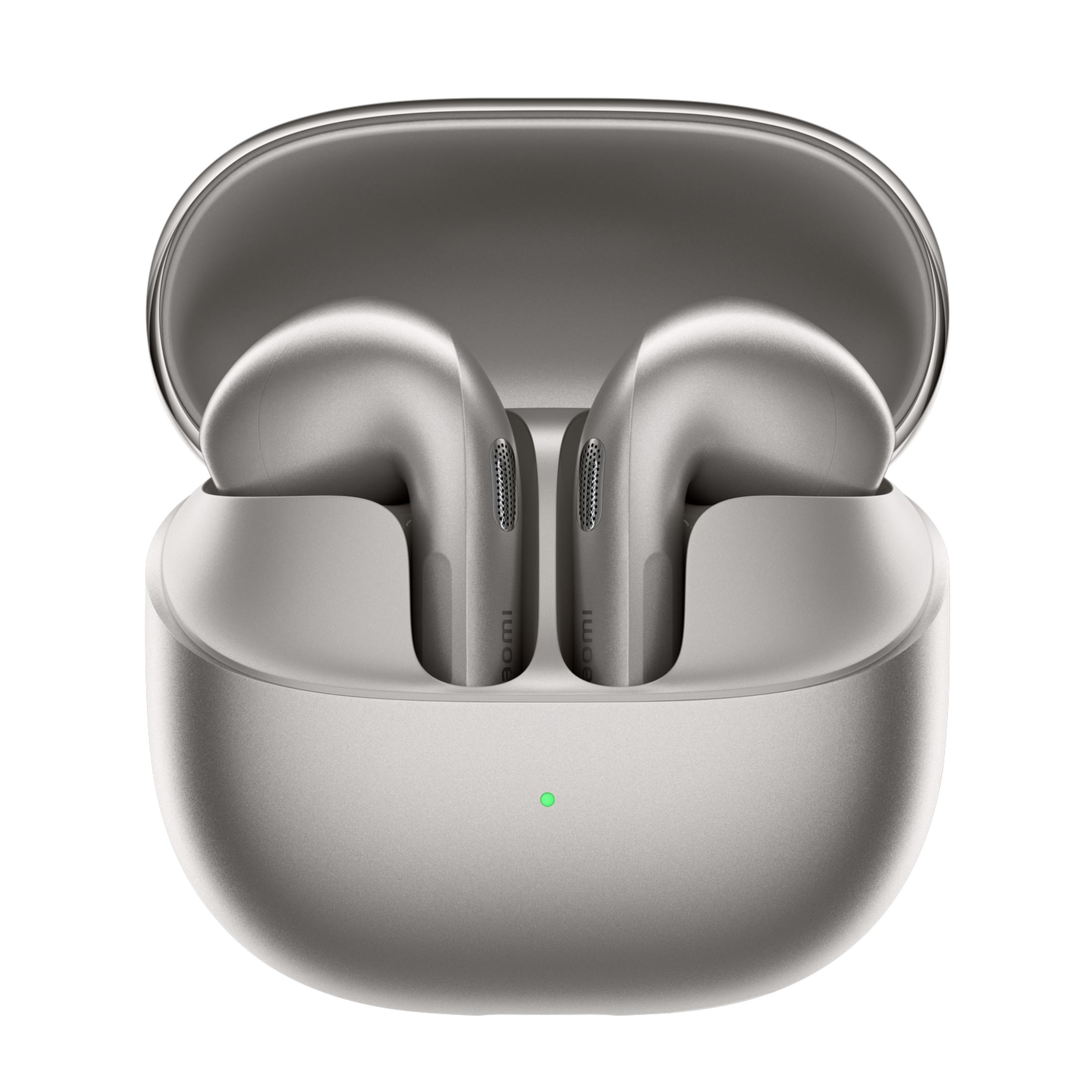 Auriculares inalámbricos plateados en un estuche de carga abierto con luz indicadora verde.