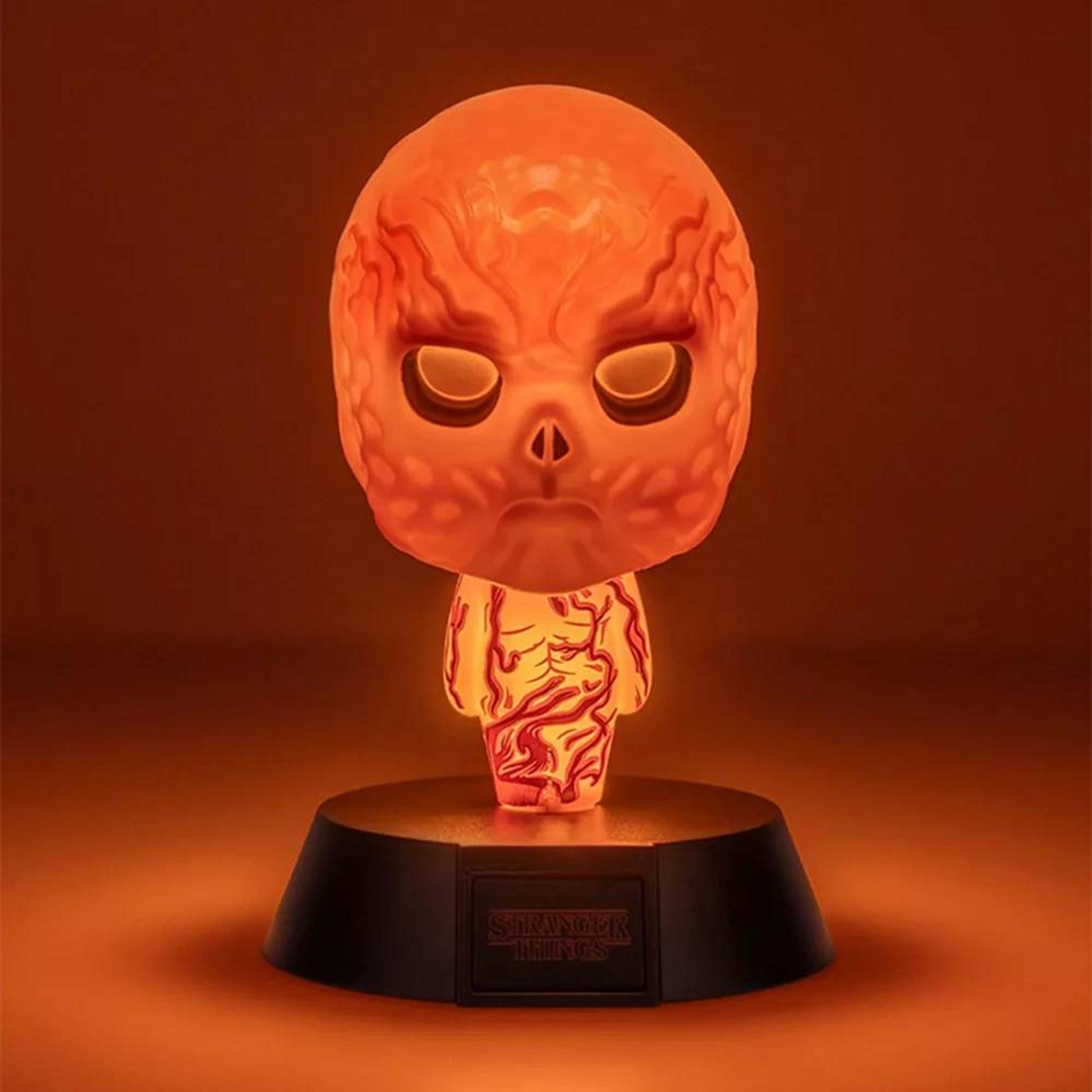 Eine leuchtende orangefarbene Figur, die einer Kreatur aus Stranger Things ähnelt, sitzt auf einem schwarzen Ständer.