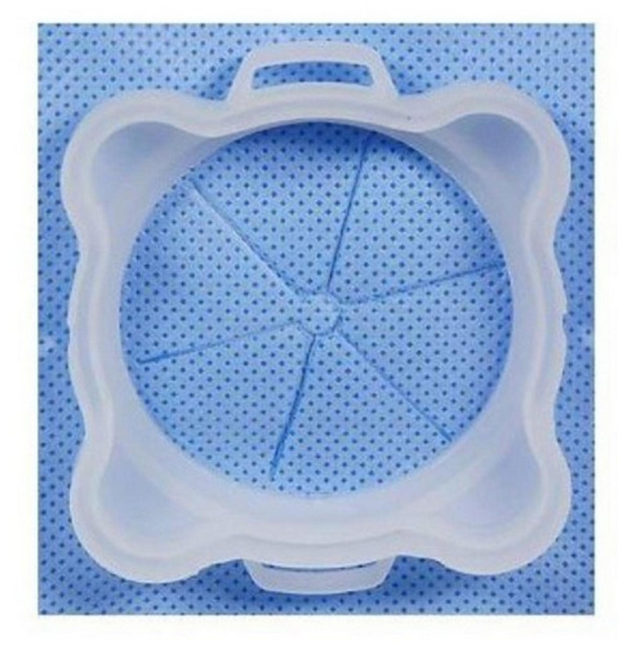 Un anello in silicone bianco con manici poggia su un tessuto blu a pois.