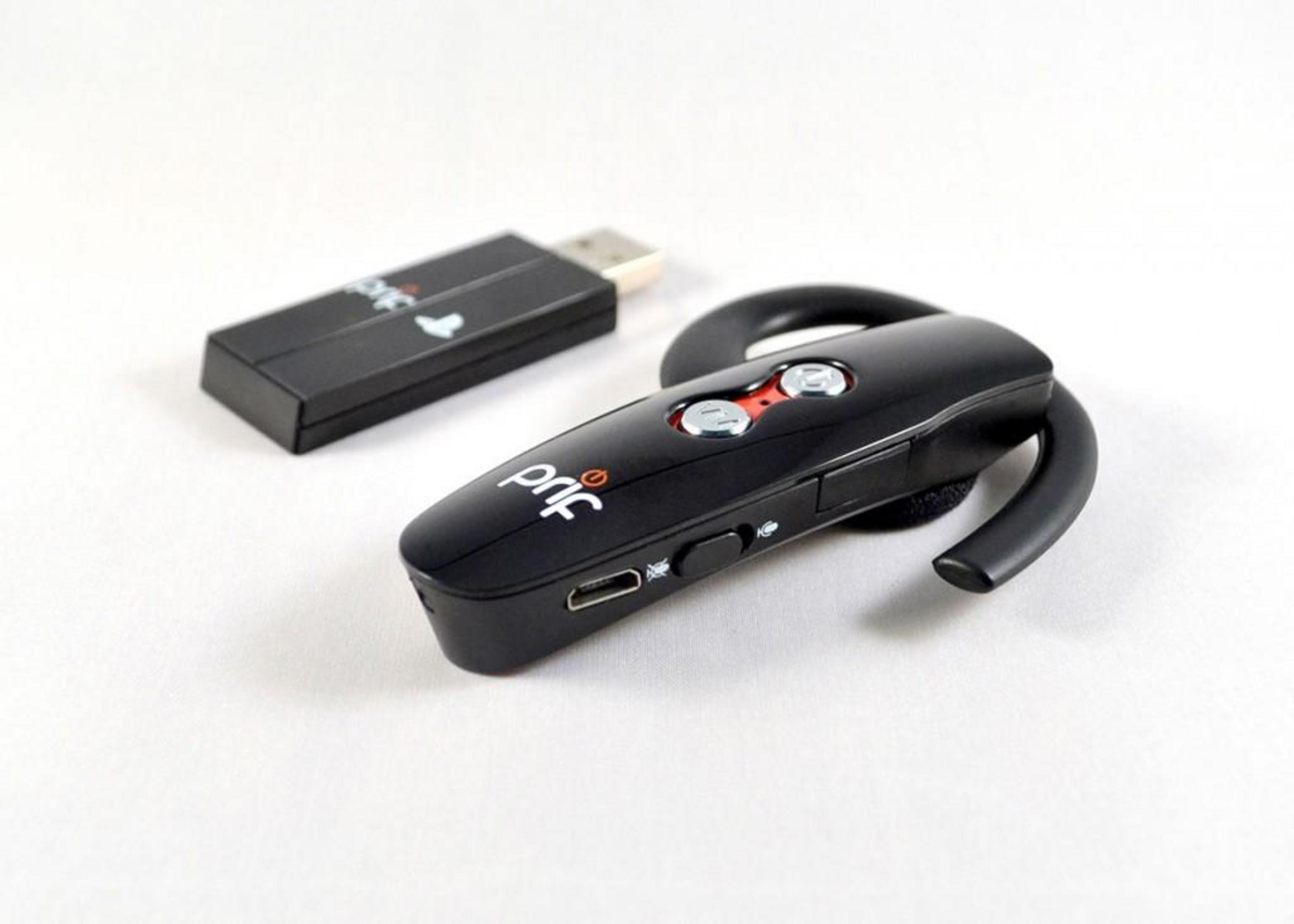 Un auricolare nero e un dongle USB su una superficie bianca.