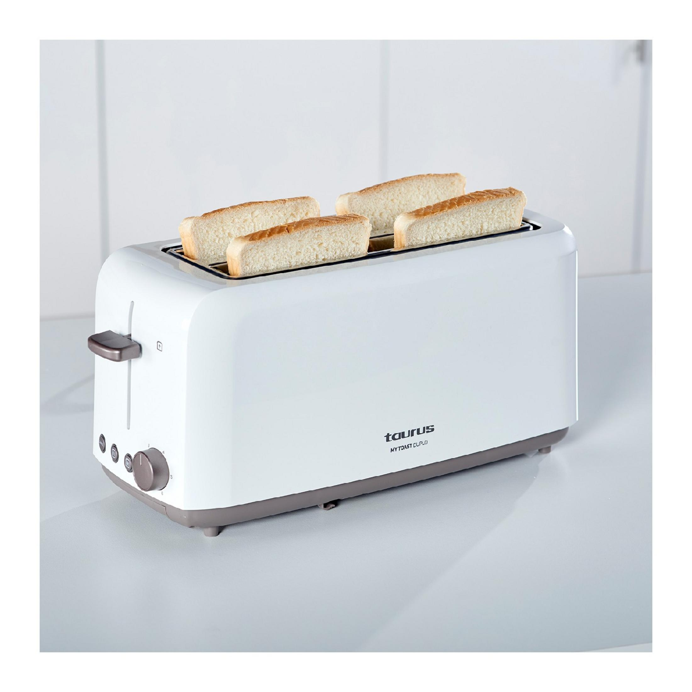 Un tostapane bianco con quattro fette di pane nelle sue fessure su un piano di lavoro chiaro.