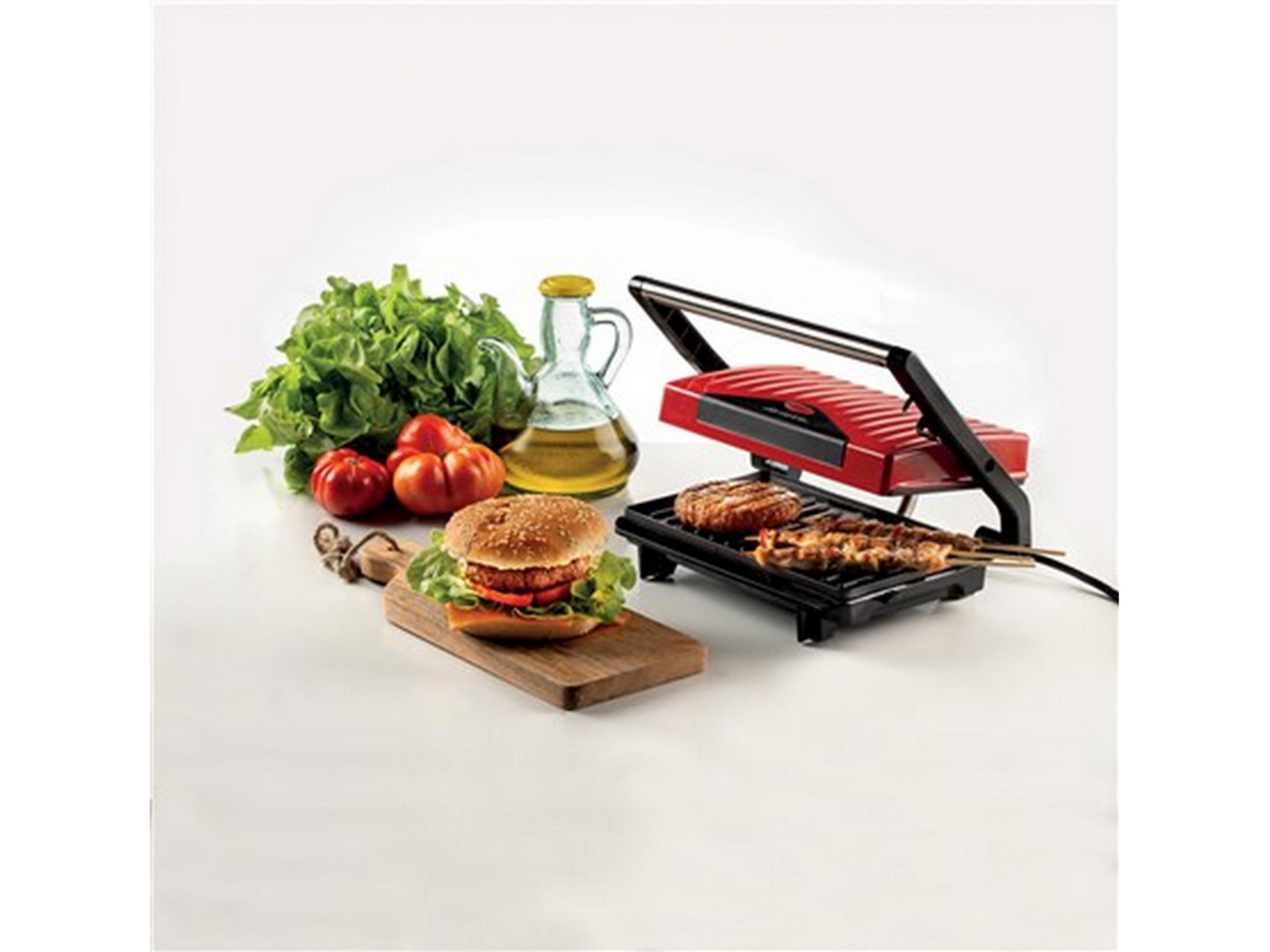 Una parrilla de contacto roja con hamburguesa y brochetas. A su lado hay ensalada y tomates.