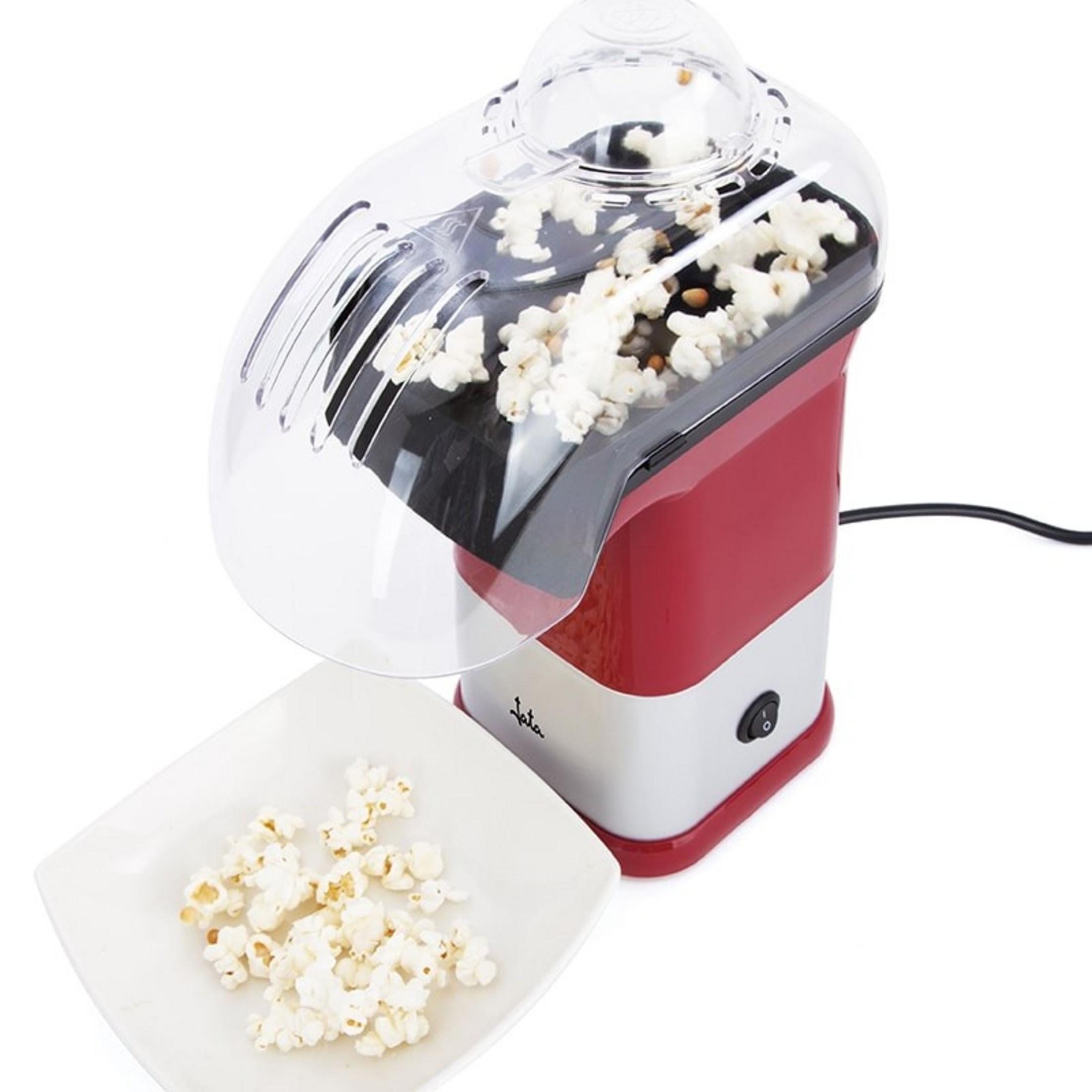 Una macchina per popcorn rossa e bianca con popcorn all'interno e su un piatto.