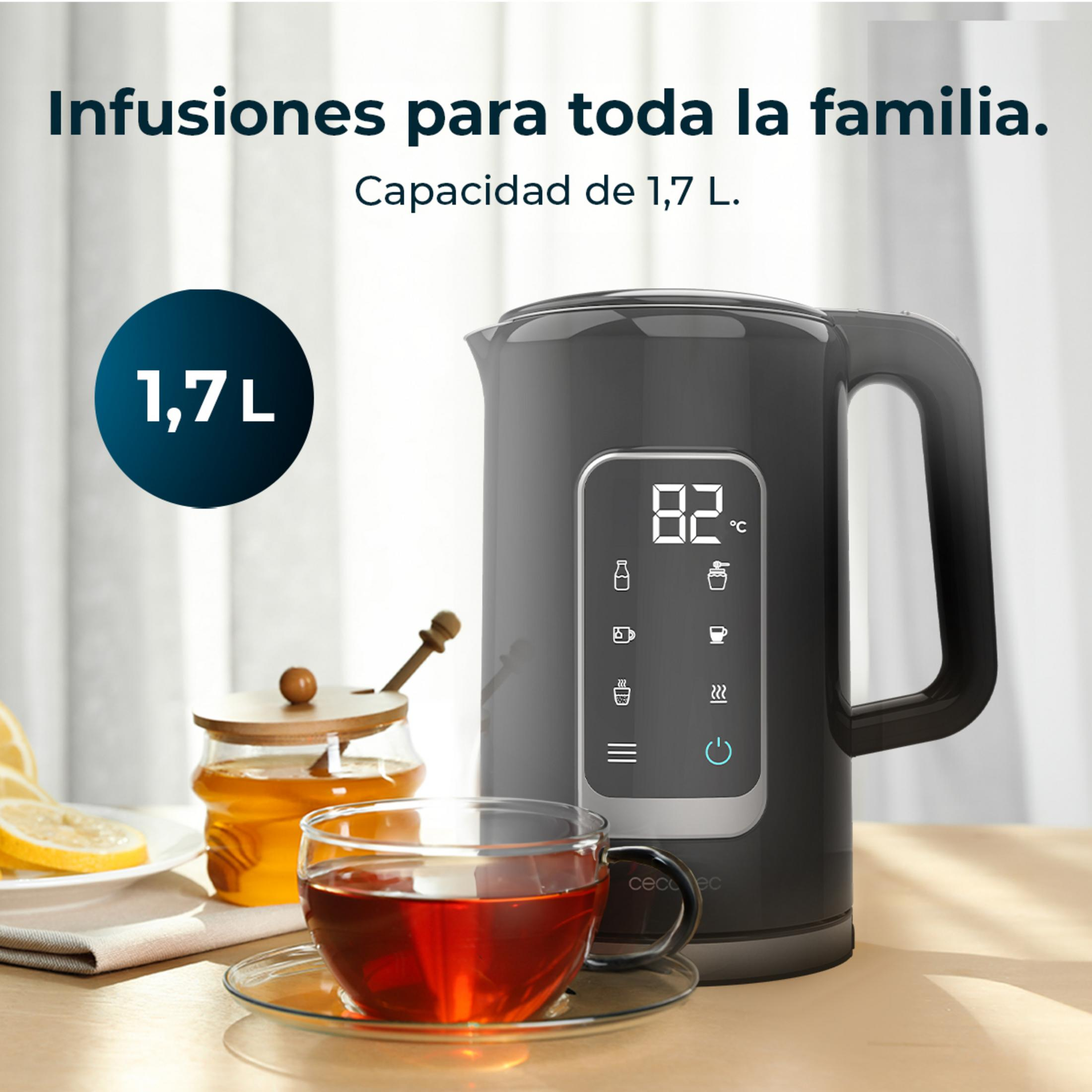 Un bollitore elettrico nero con display digitale mostra 82°C, accanto a una tazza di tè e miele.