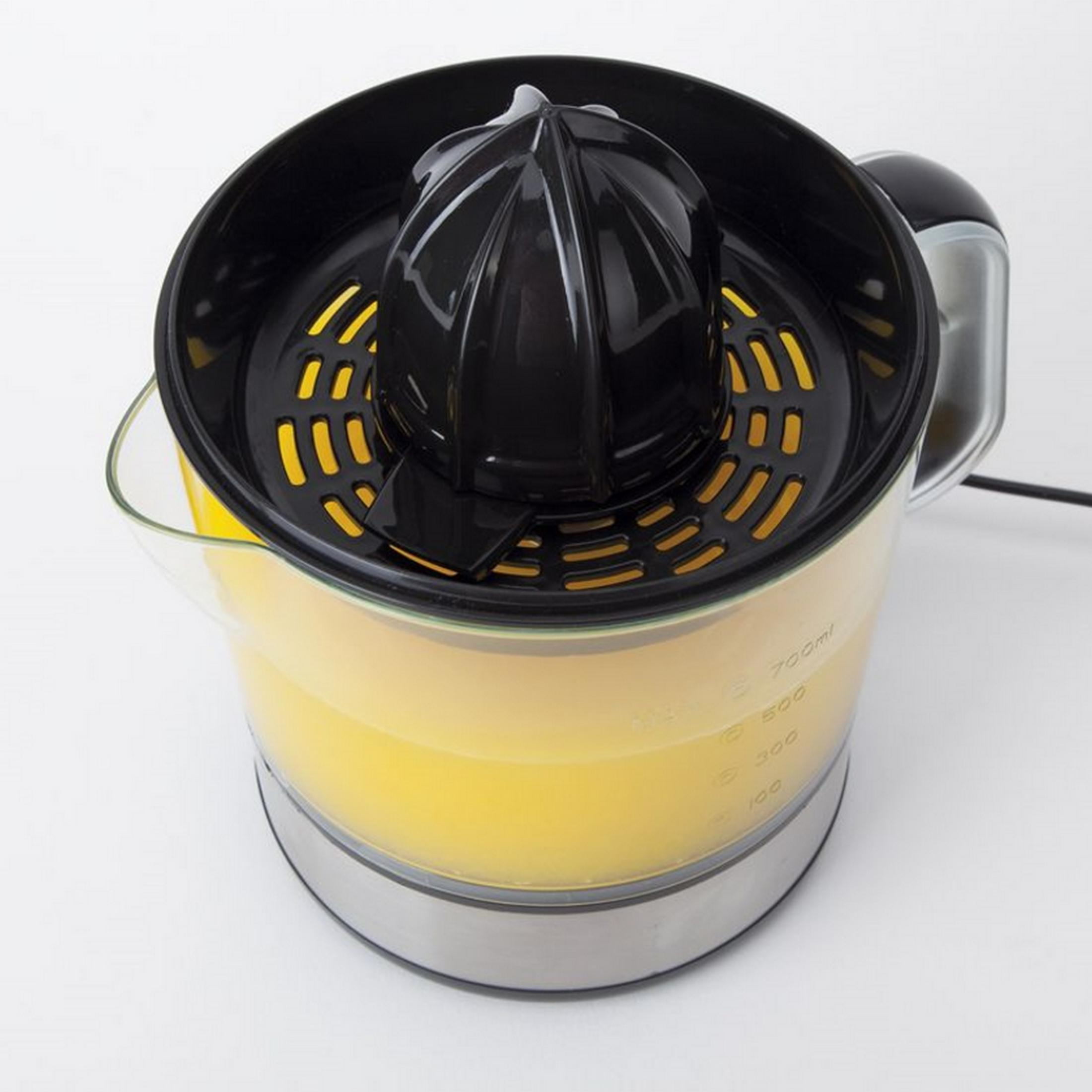 Un exprimidor de cítricos eléctrico con jugo amarillo en un recipiente transparente.