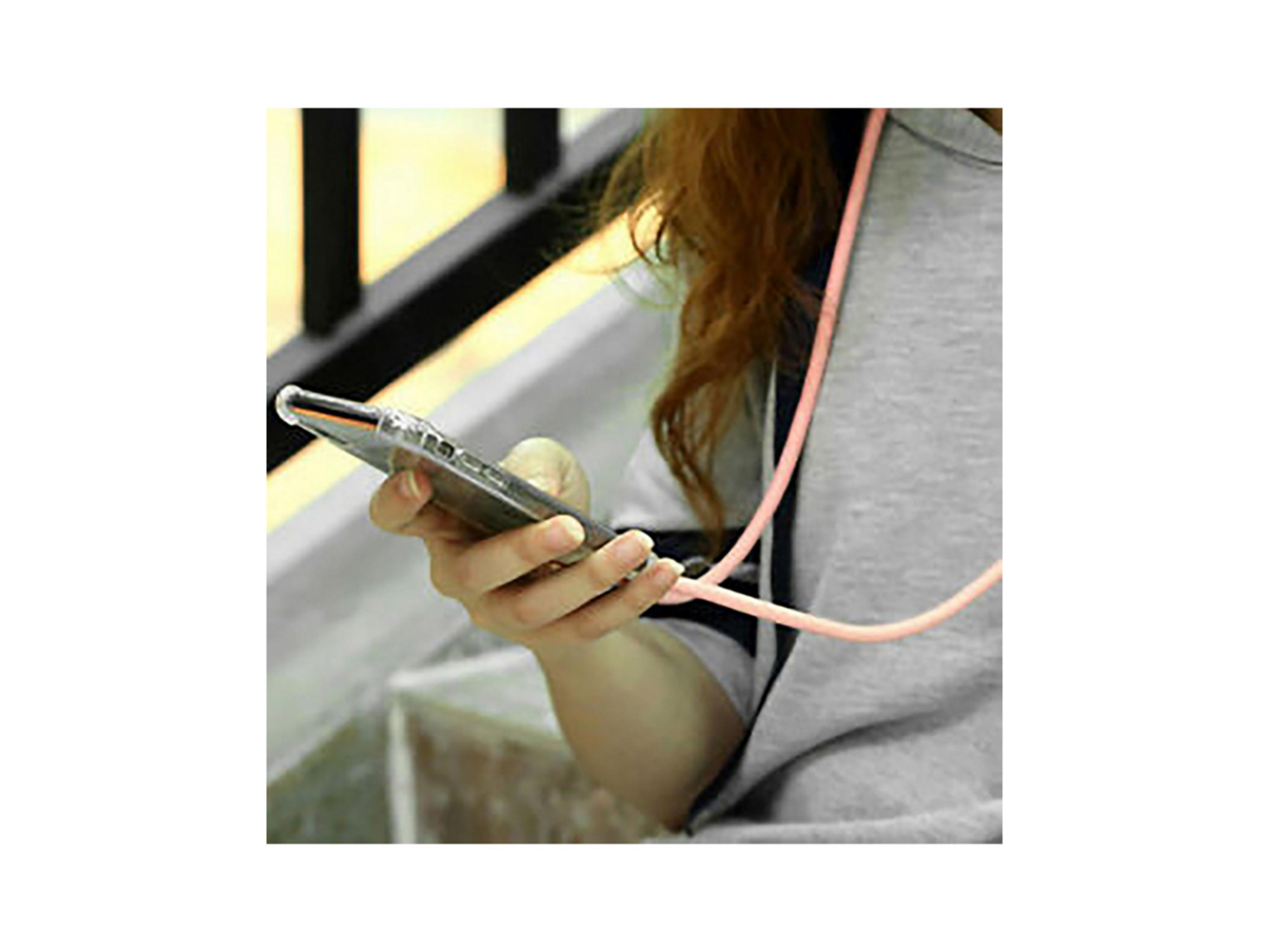Una mujer sostiene un smartphone con funda transparente y cordón rosa.
