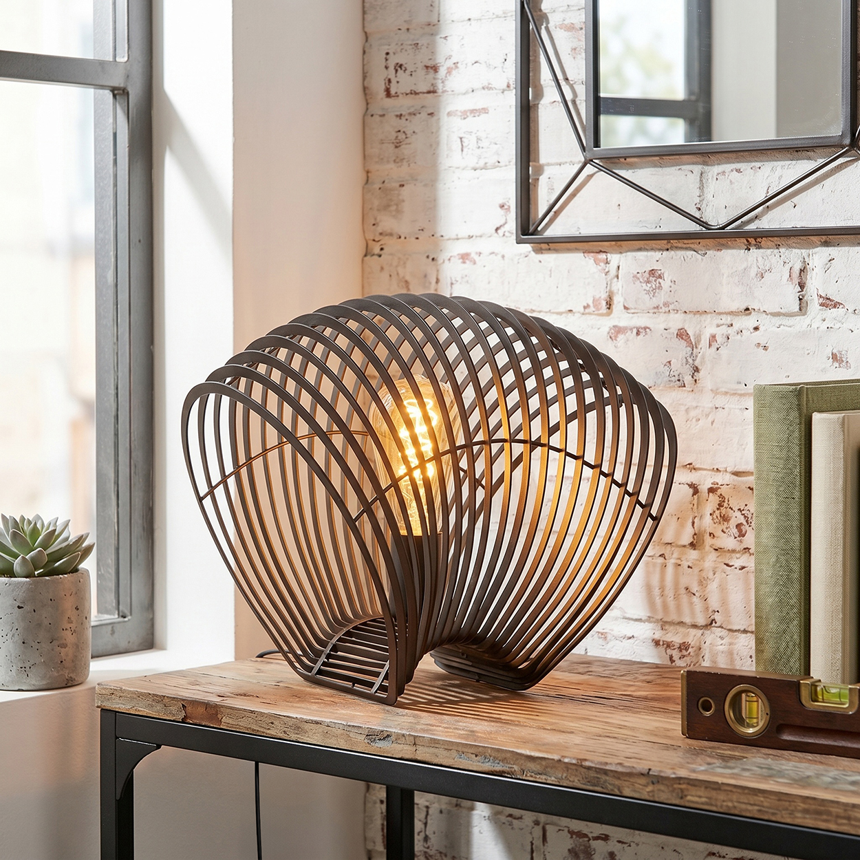 Eine moderne Lampe mit Drahtgestell und Glühbirne steht auf einem Holztisch.