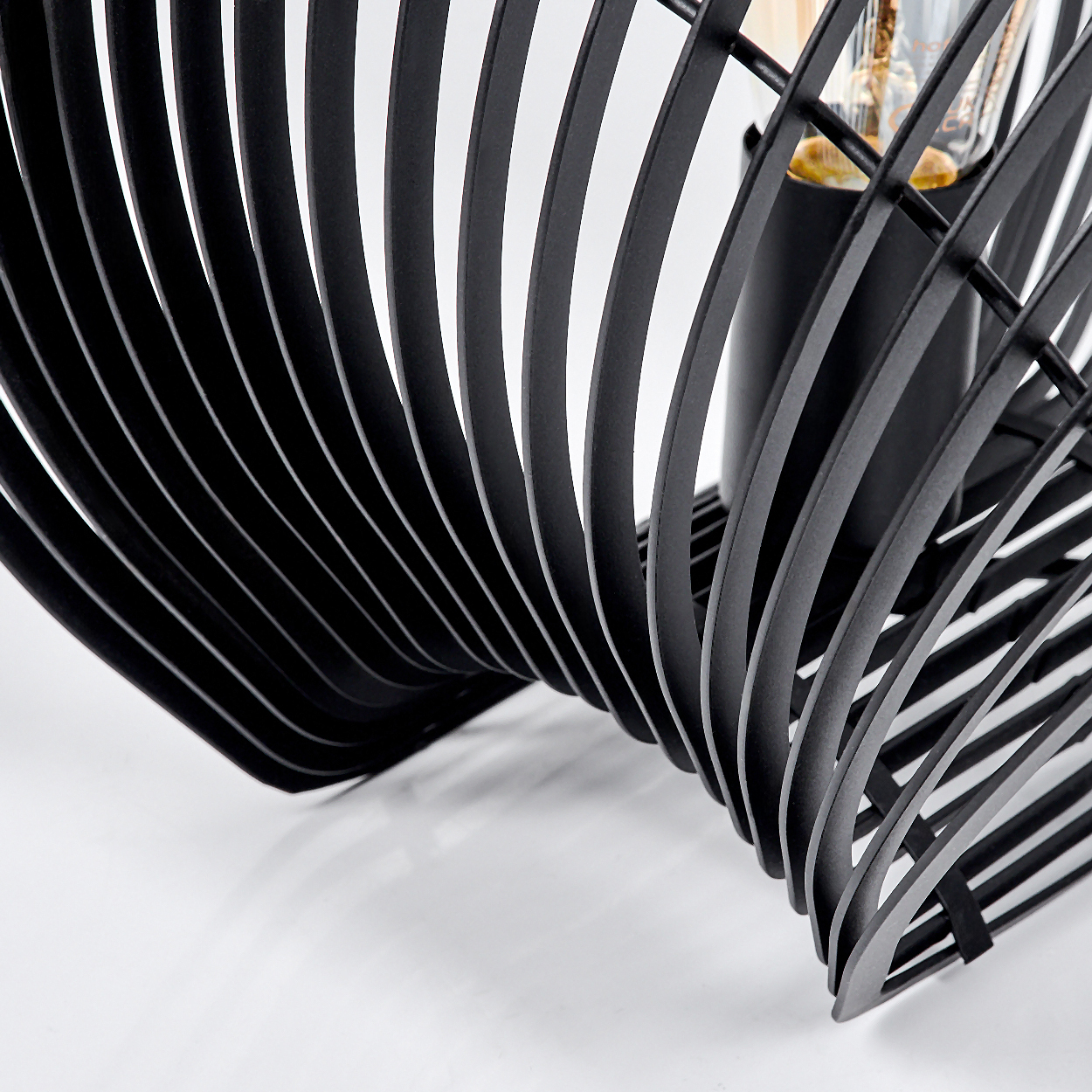 Schwarze Metalllampe mit Spiraldesign und sichtbarer Glühbirne.