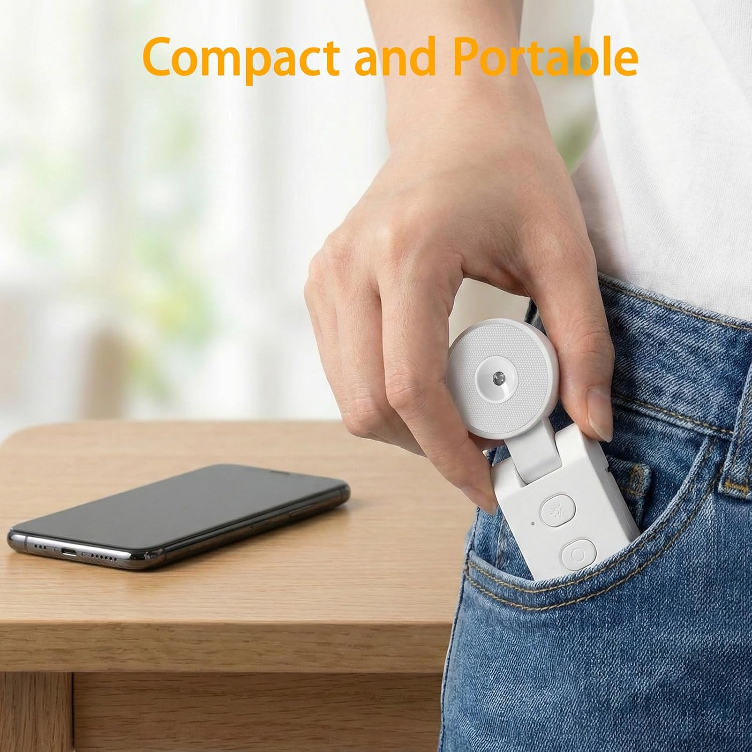 Eine Hand steckt ein kleines weißes Gerät in eine Jeanstasche. Ein Smartphone liegt auf einem Holztisch.