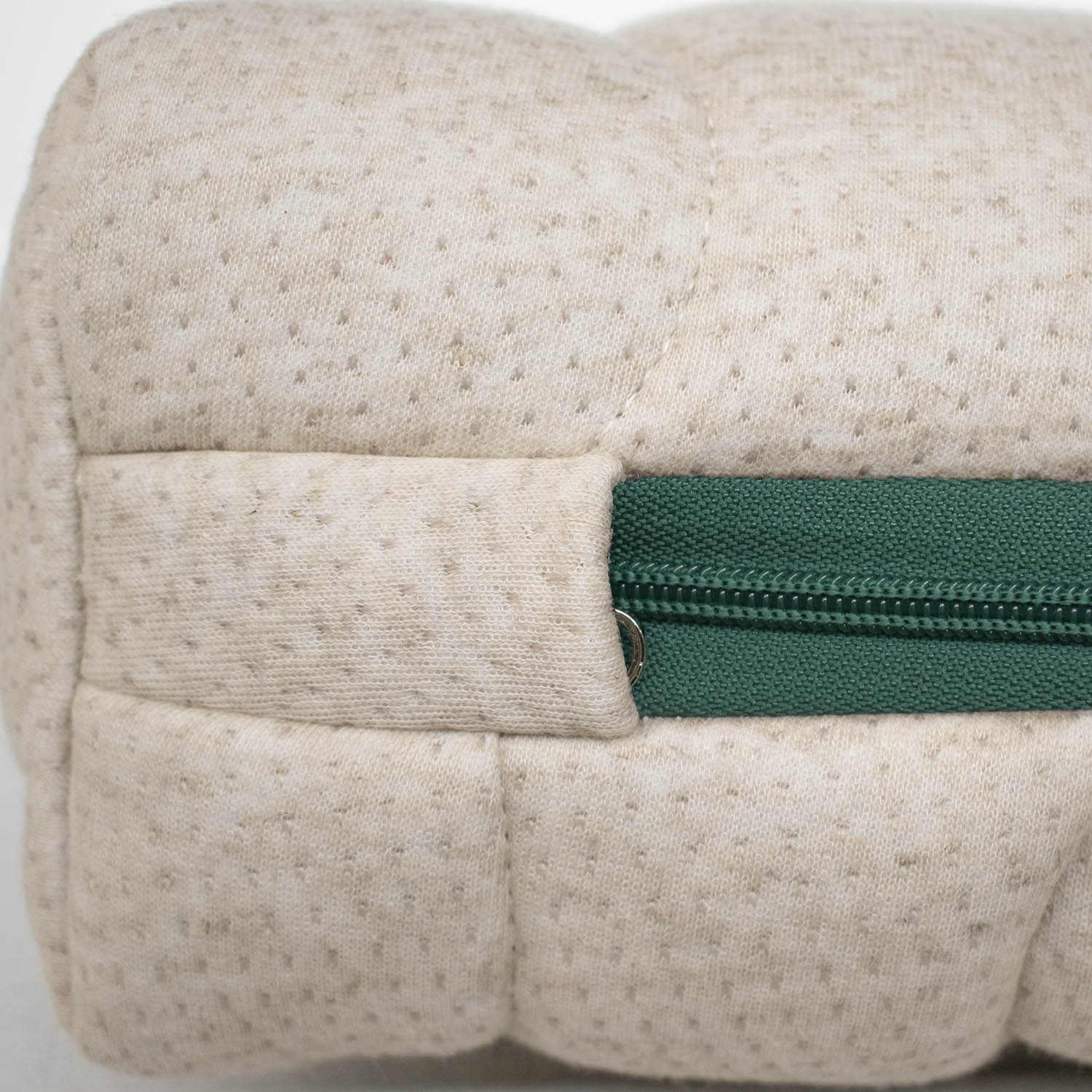 Primer plano de una superficie acolchada beige con cremallera verde.