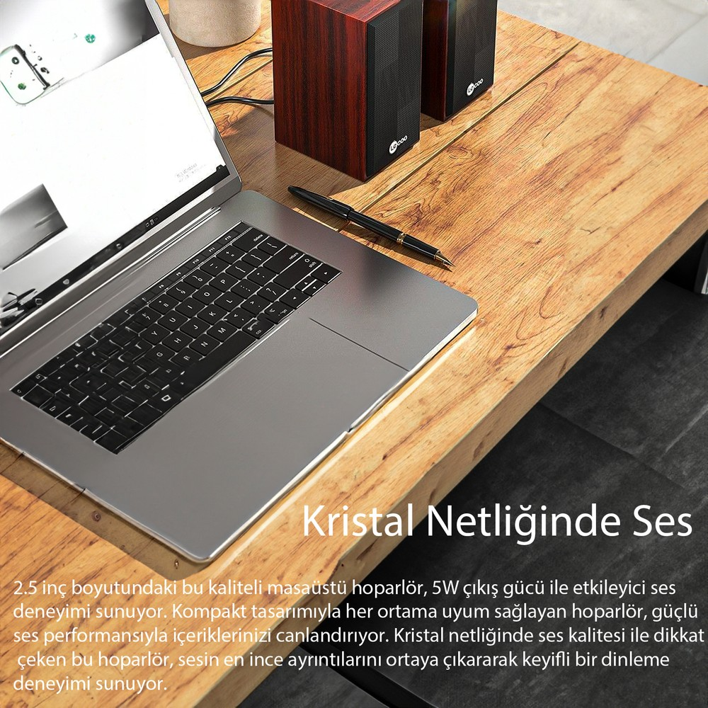Laptop, kalem ve iki ahşap hoparlör ahşap masa üzerinde.