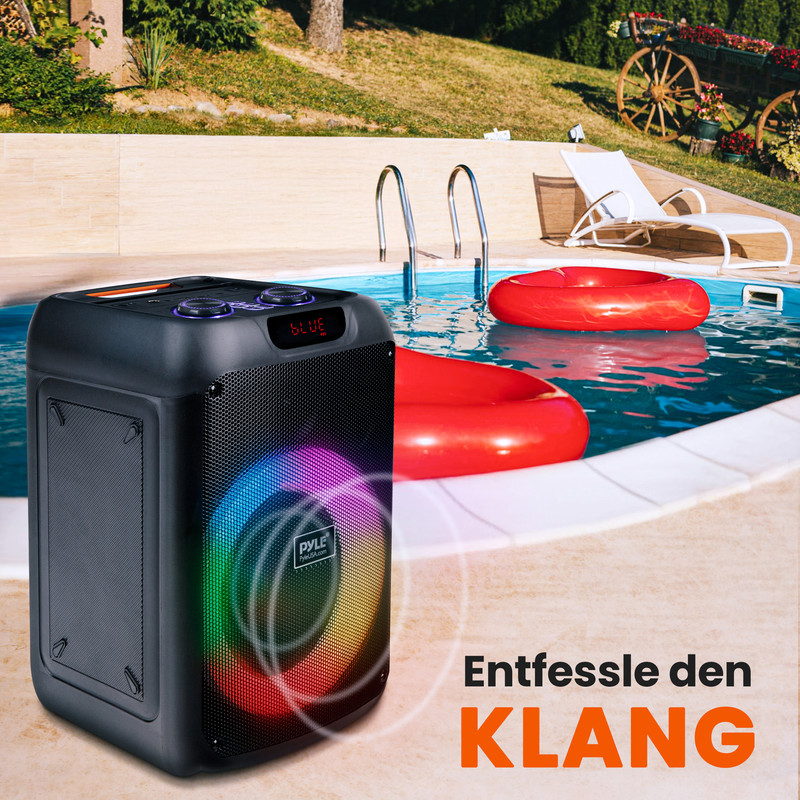 Ein schwarzer Lautsprecher mit bunten Lichtern steht neben einem Pool mit roten Schwimmringen.