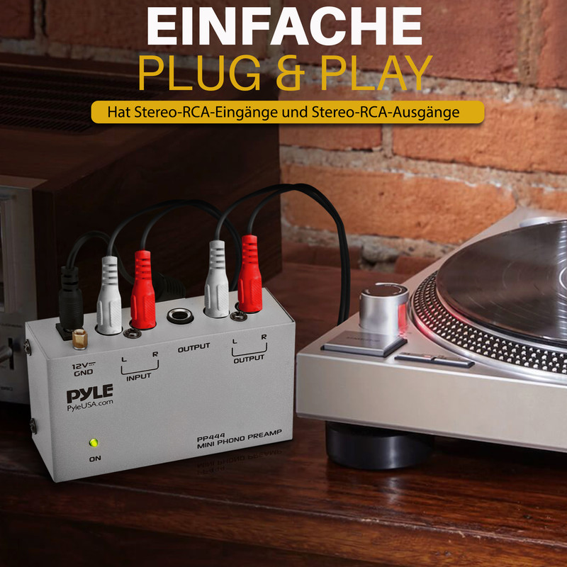 Grauer Mini-Phono-Vorverstärker mit Kabeln, verbunden mit einem Plattenspieler.