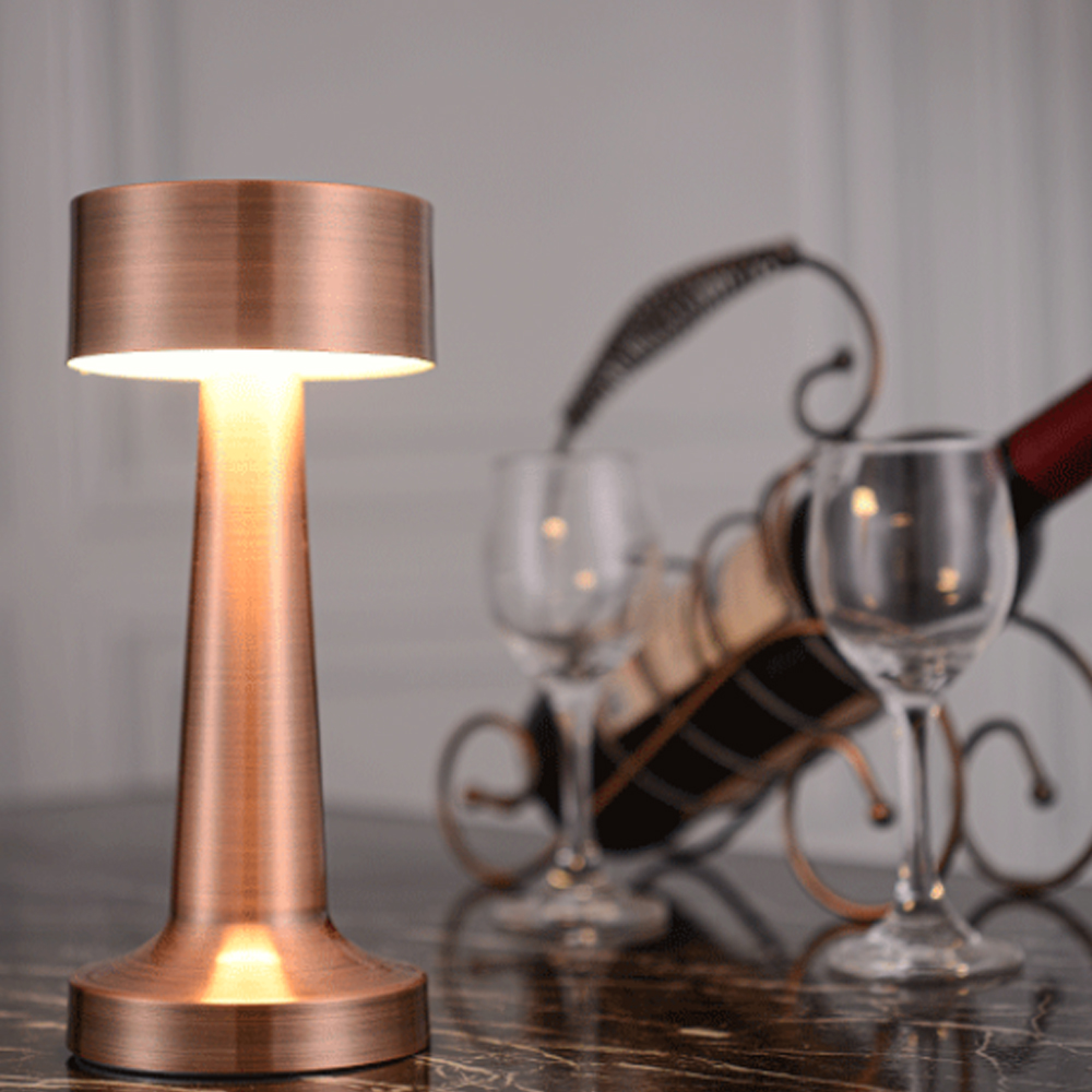 Eine kupferfarbene Lampe steht neben Weingläsern und einem Weinregal.
