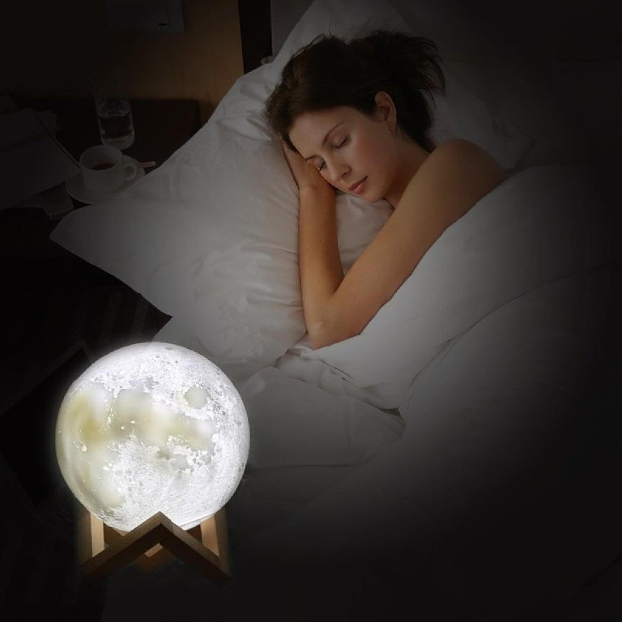 Eine Frau schläft im Bett neben einem Mondlicht.