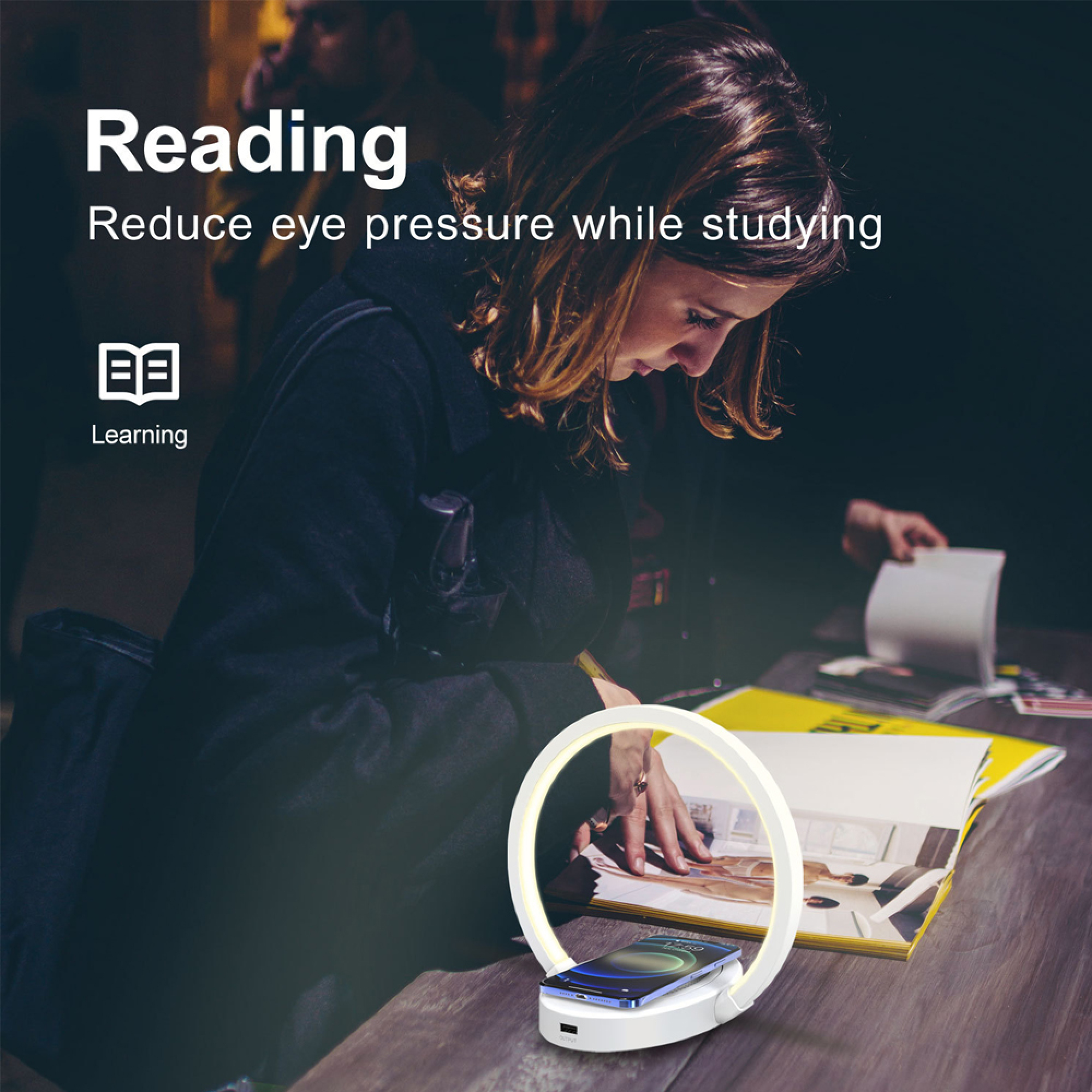 Frau liest in einem Buch, das von einer Ringlampe beleuchtet wird. Ein Smartphone lädt.