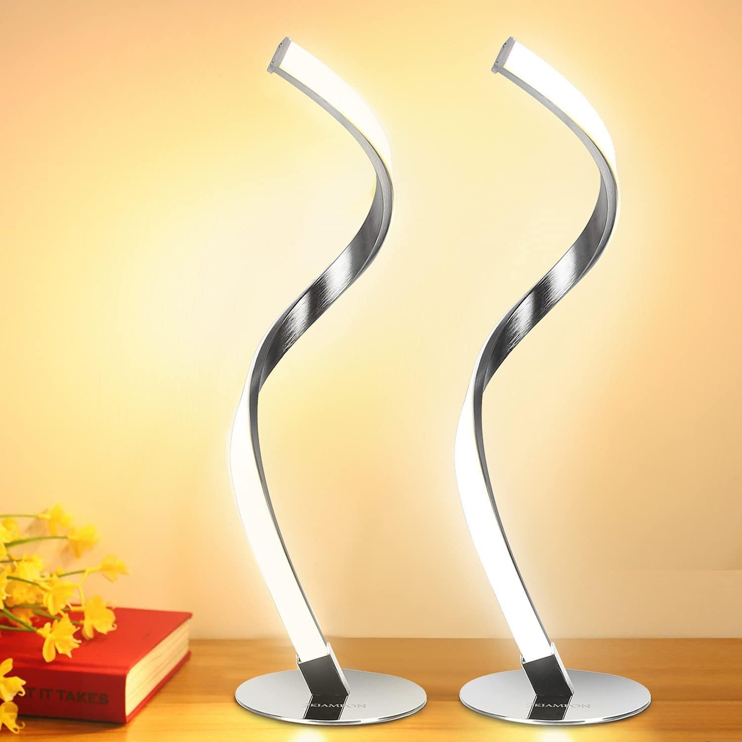 Zwei moderne Schreibtischlampen mit geschwungenem Design und LED-Beleuchtung auf einem Holztisch.