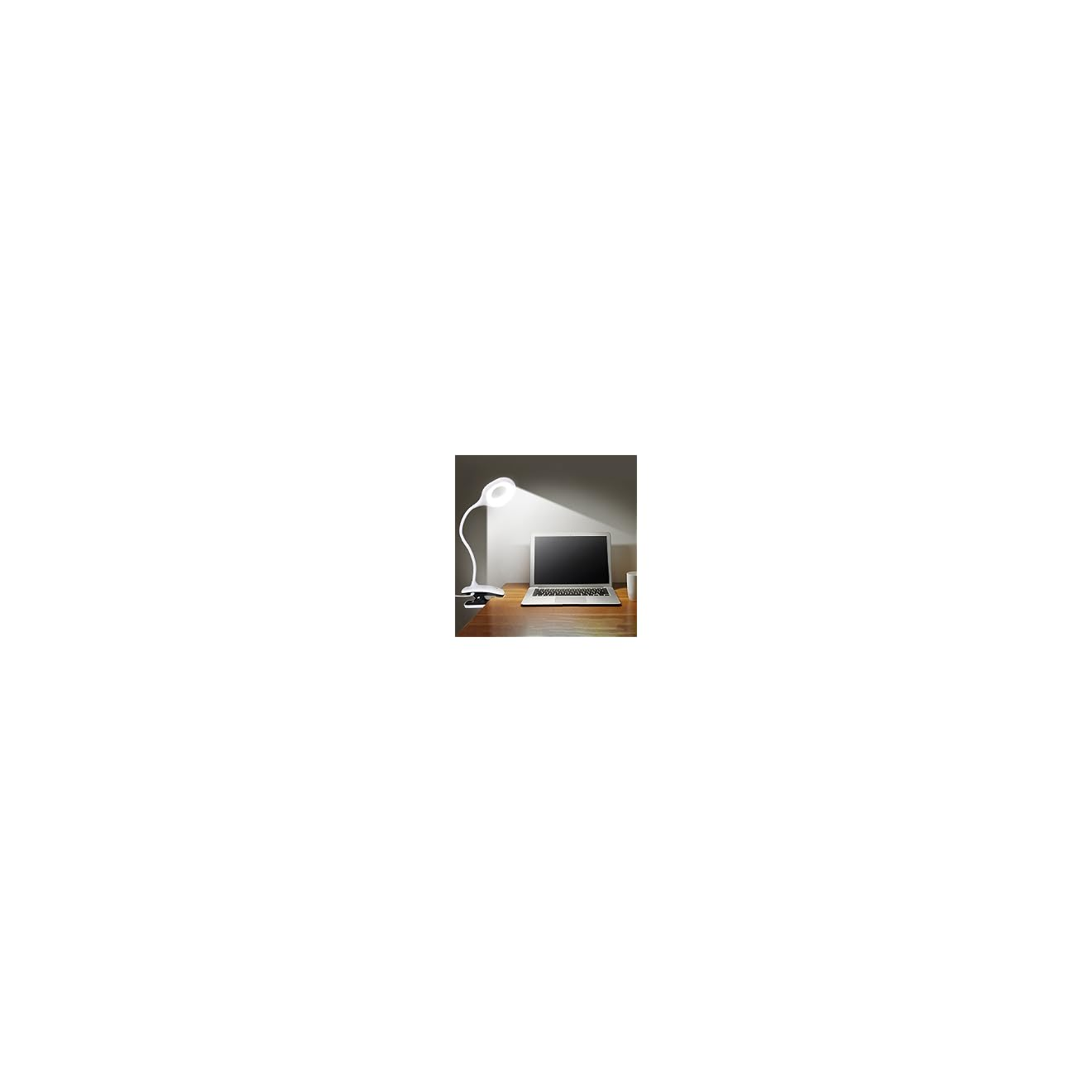Ein Laptop steht auf einem Holztisch neben einer weißen Klemmleuchte.