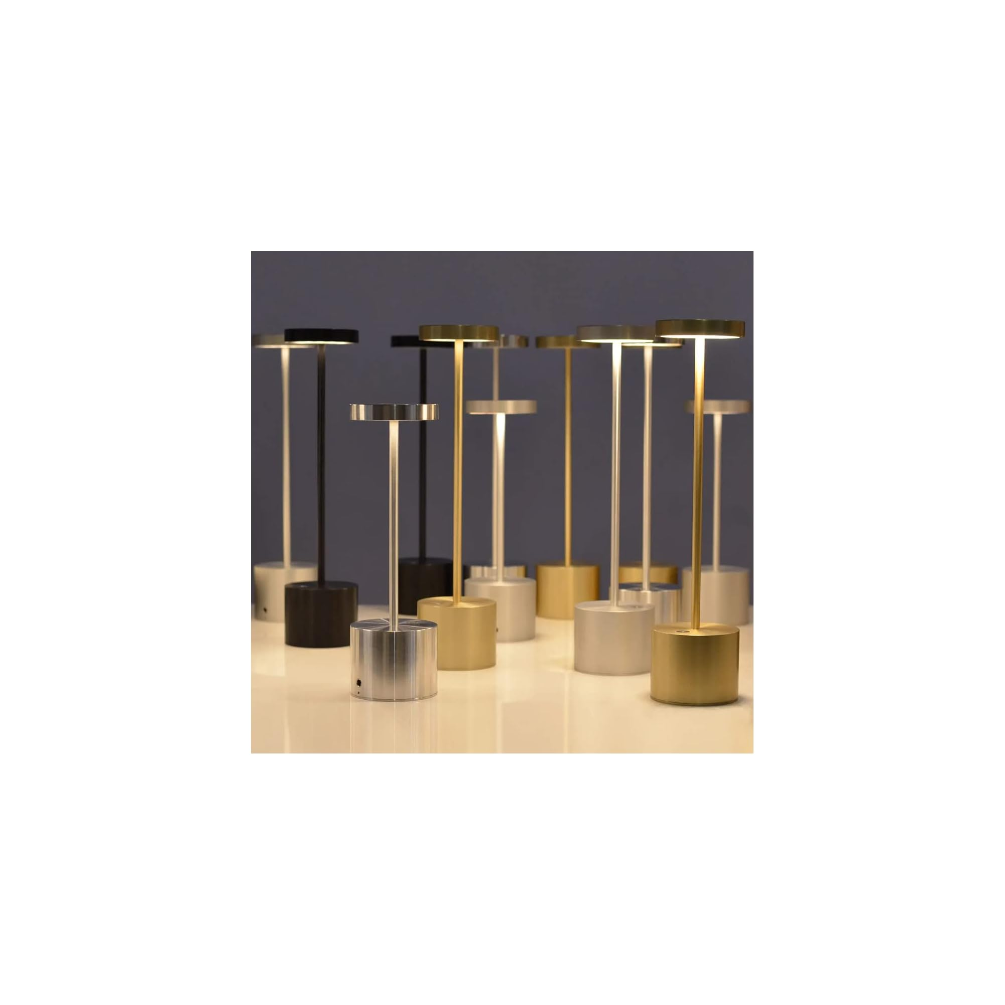 Mehrere moderne Tischlampen in verschiedenen Metallfarben stehen auf einer Tischplatte.