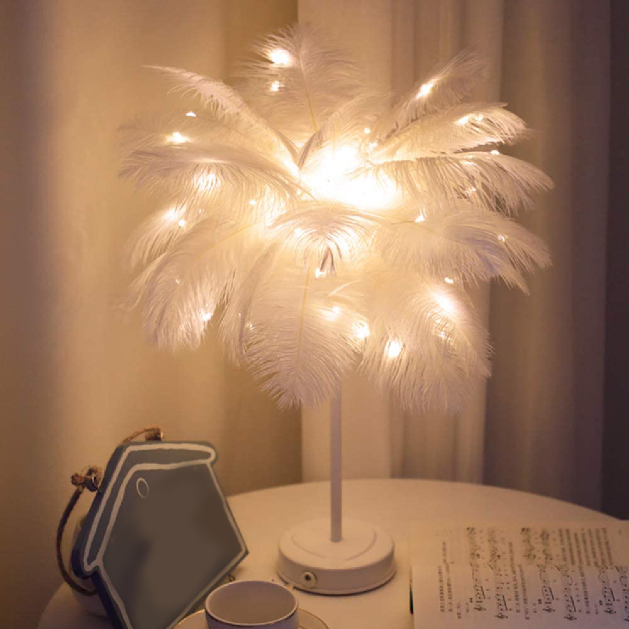 Eine weiße Federlampe mit Lichterkette auf einem Tisch mit Noten.