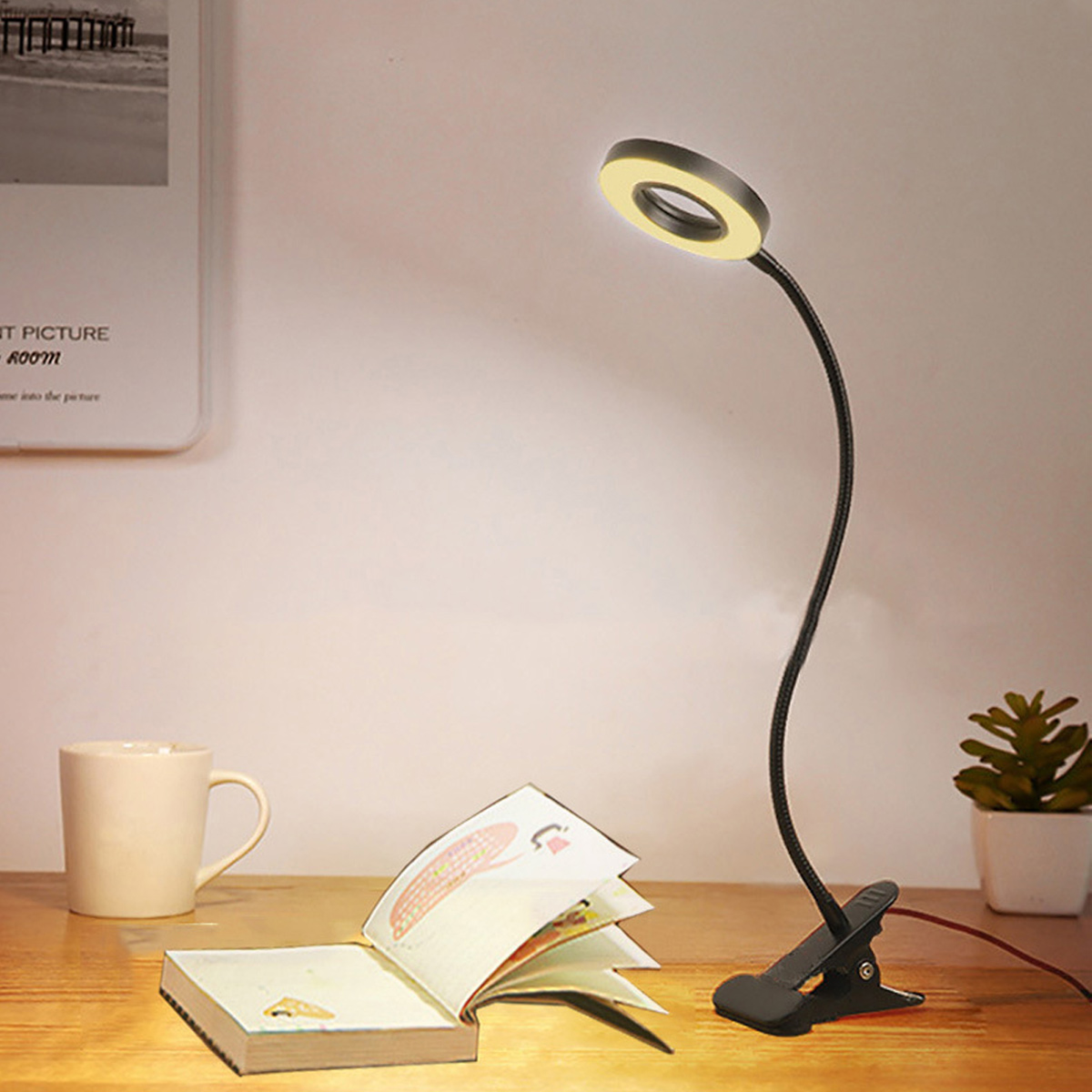 Ein Schreibtisch mit einem Buch, einer Tasse und einer Klemmleuchte.