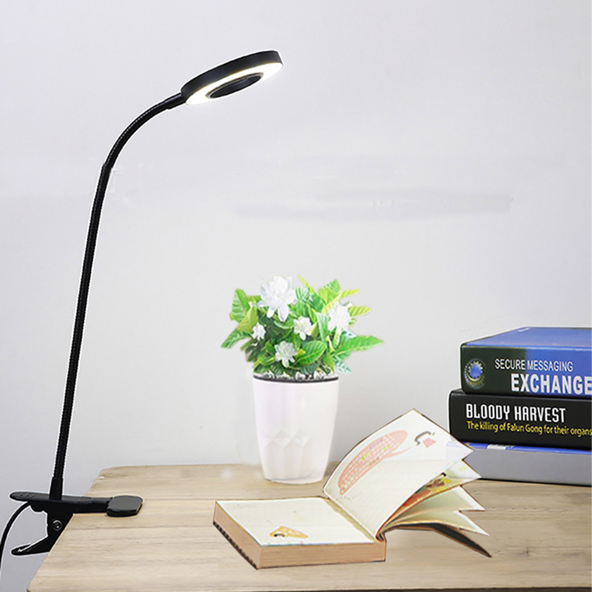 Ein schwarzer Klemm-Schreibtisch mit LED-Ringlicht, Buch, Topfpflanze und Büchern.