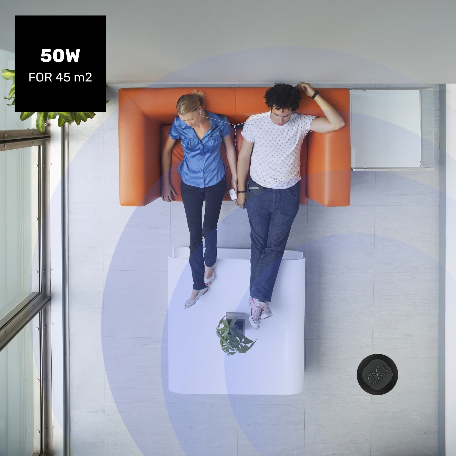 Dos personas yacen en un sofá naranja, escuchando música. Un cartel dice "50W PARA 45 m2".