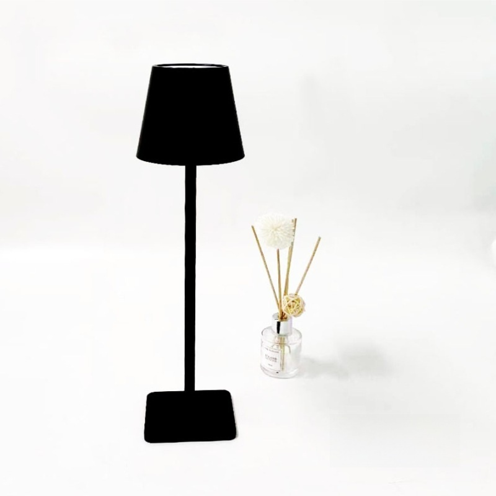 Ein schwarzer Lampenfuß mit einem Lampenschirm und einem Diffusor daneben.