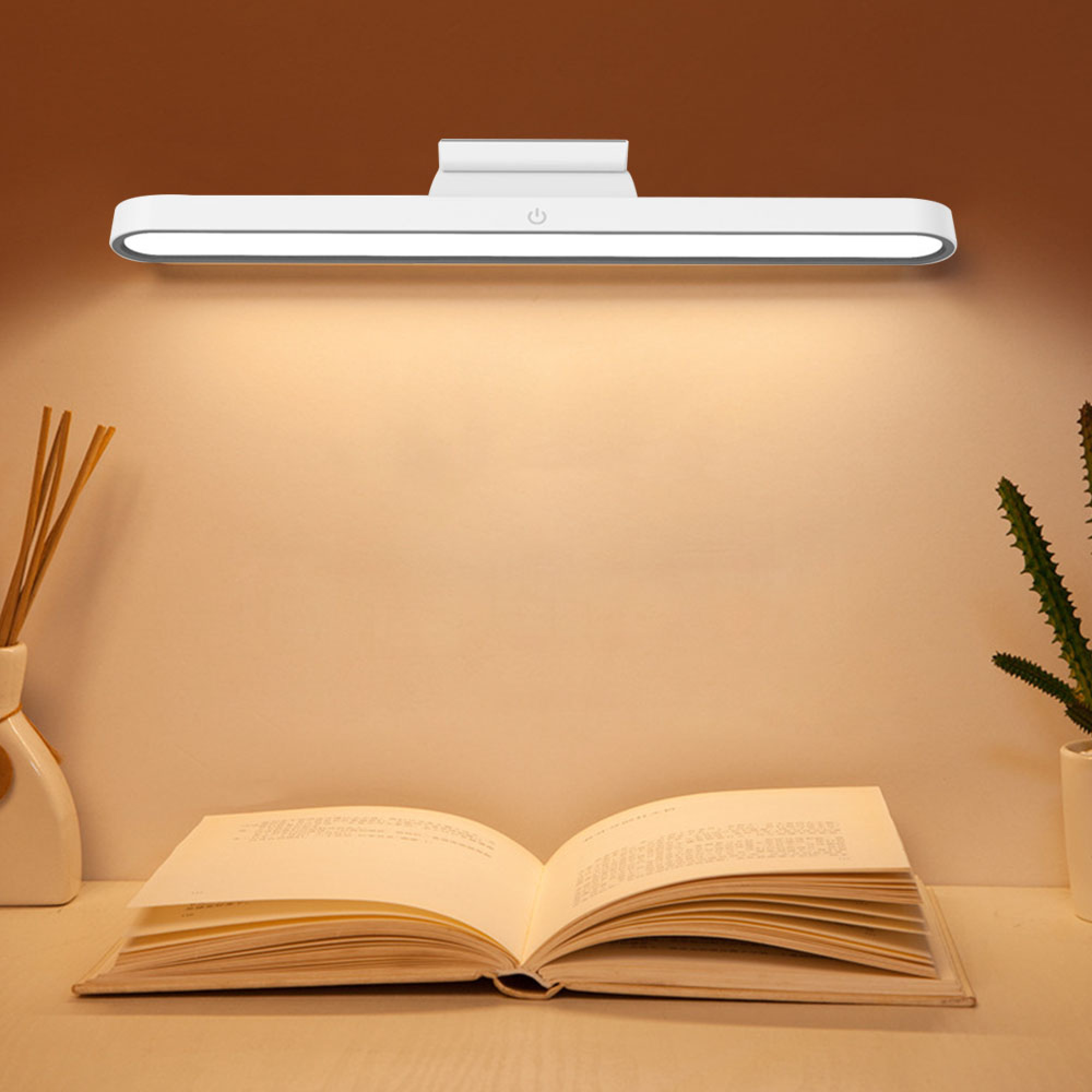 Ein offenes Buch liegt auf einem Schreibtisch, beleuchtet von einer Lampe.