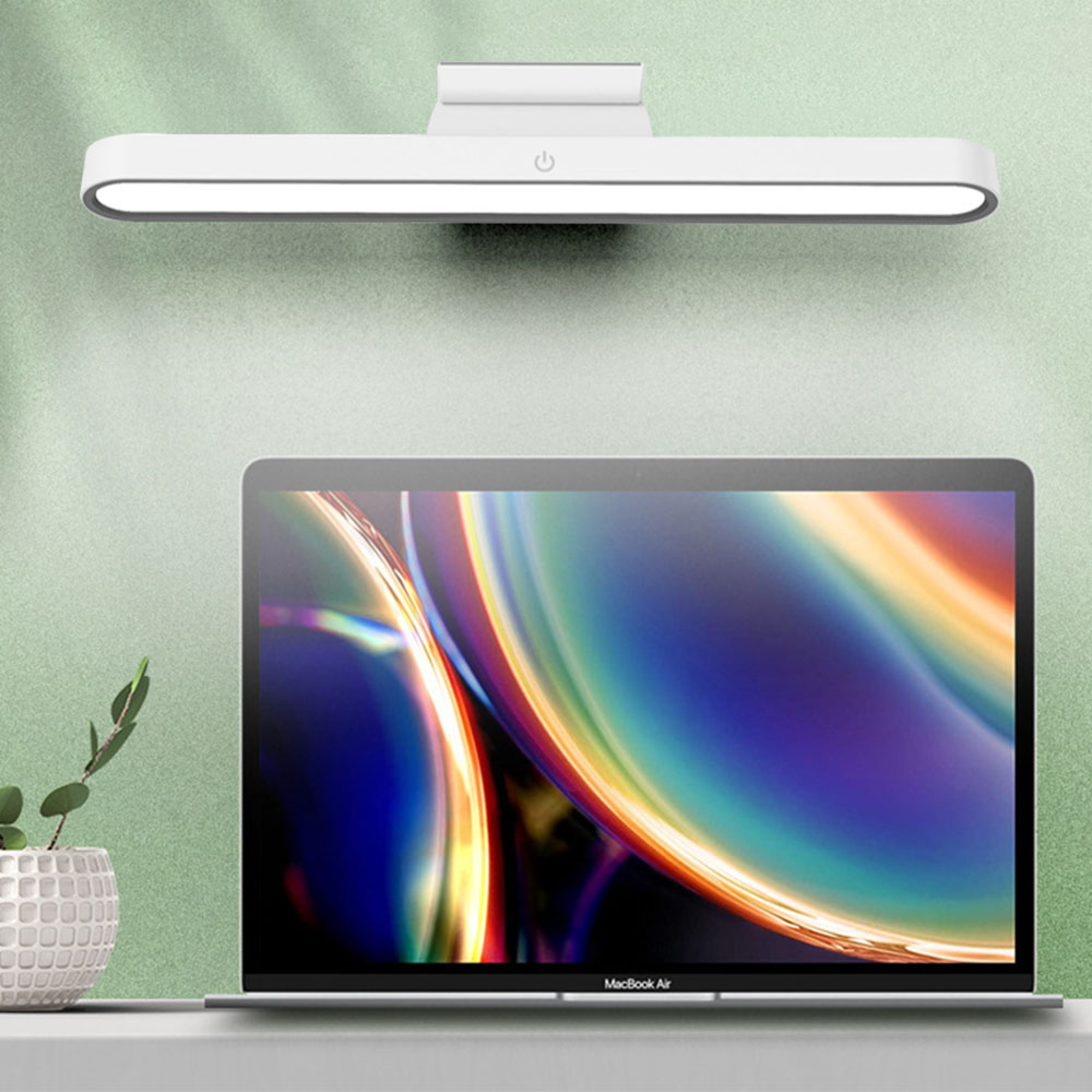 Eine weiße LED-Leuchte über einem geöffneten Laptop mit buntem Bildschirm.