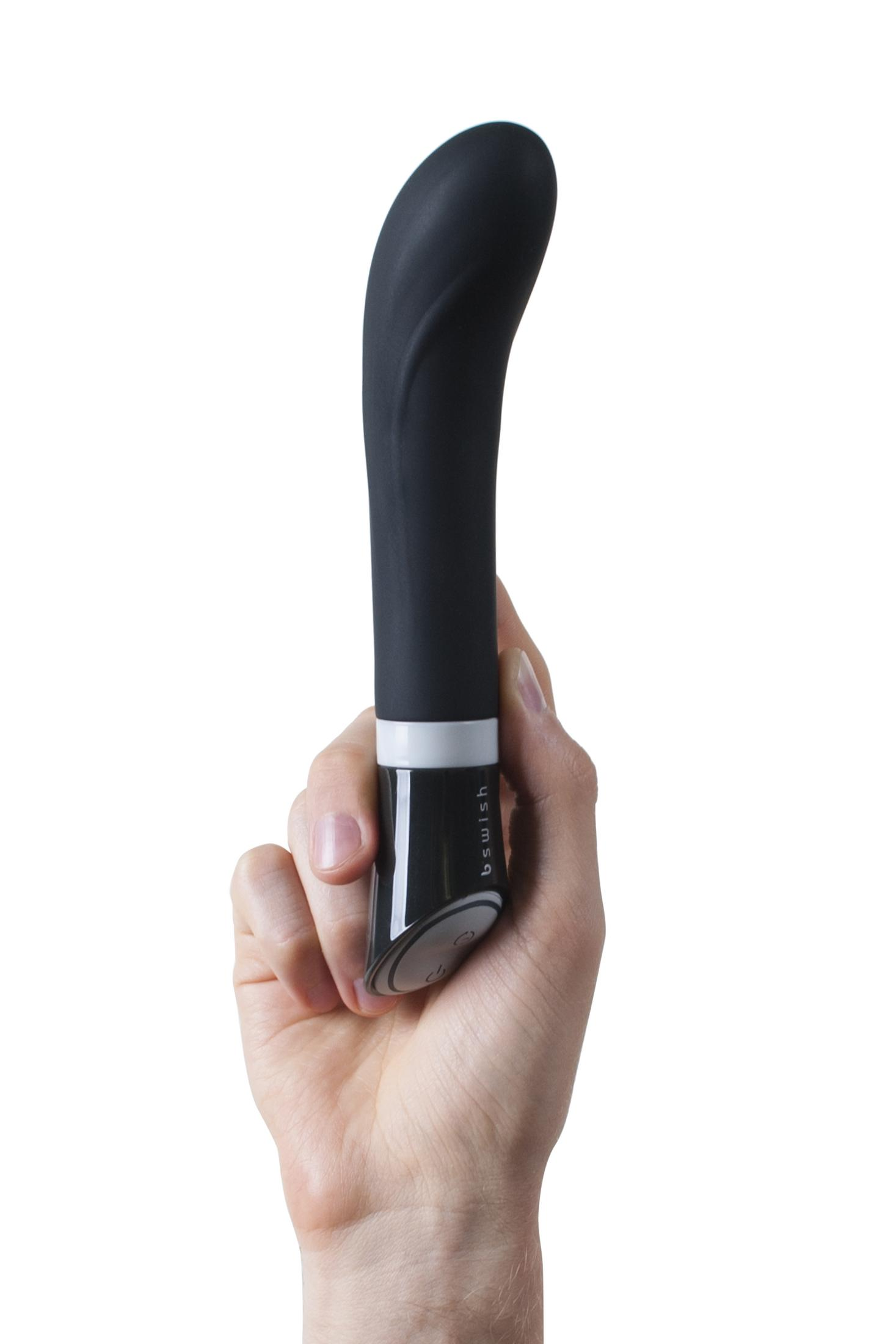 Eine Hand hält einen schwarzen Vibrator mit weißem Ring und silbernen Bedienelementen.