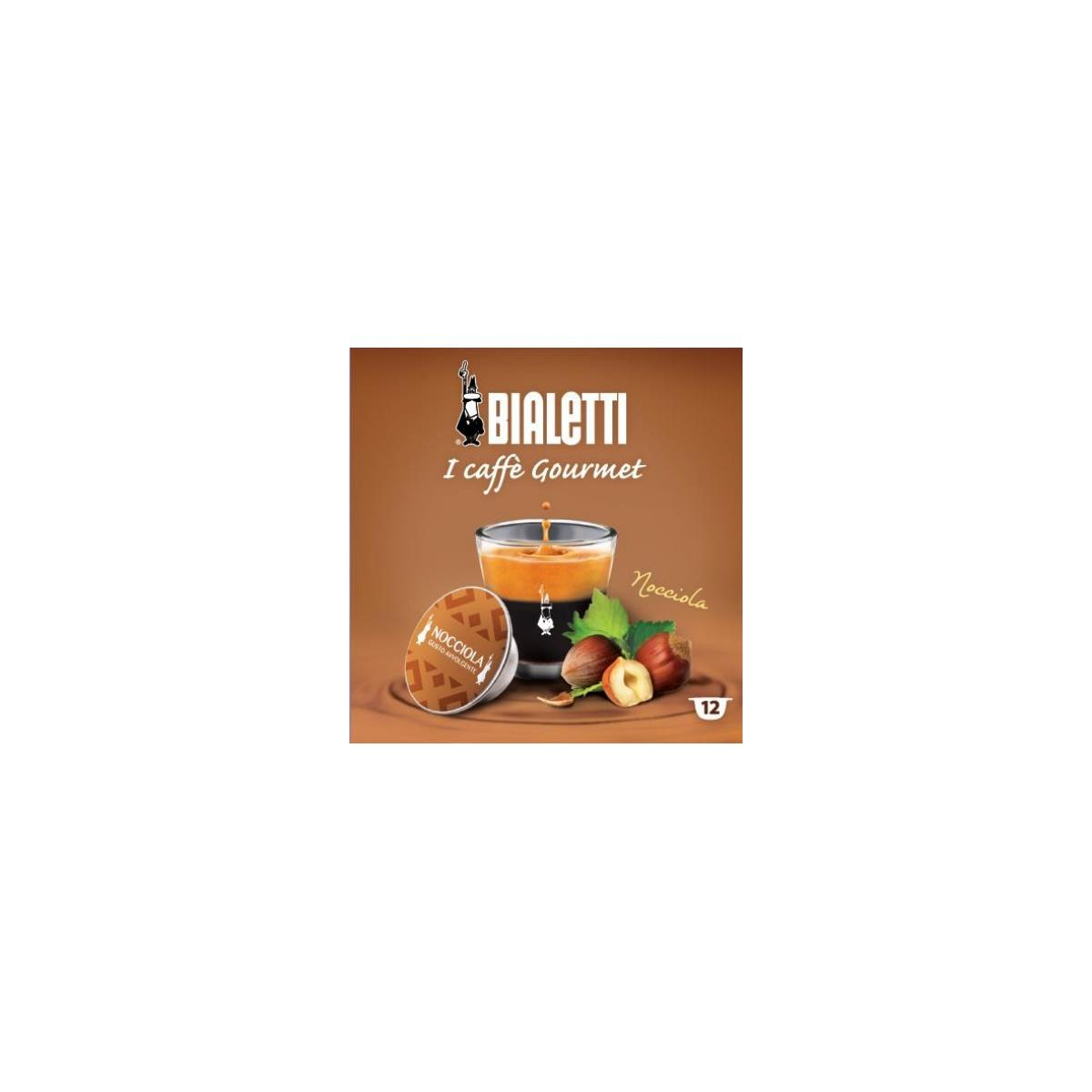 Capsula caffè Bialetti Nocciola accanto a un bicchiere di espresso e nocciole.