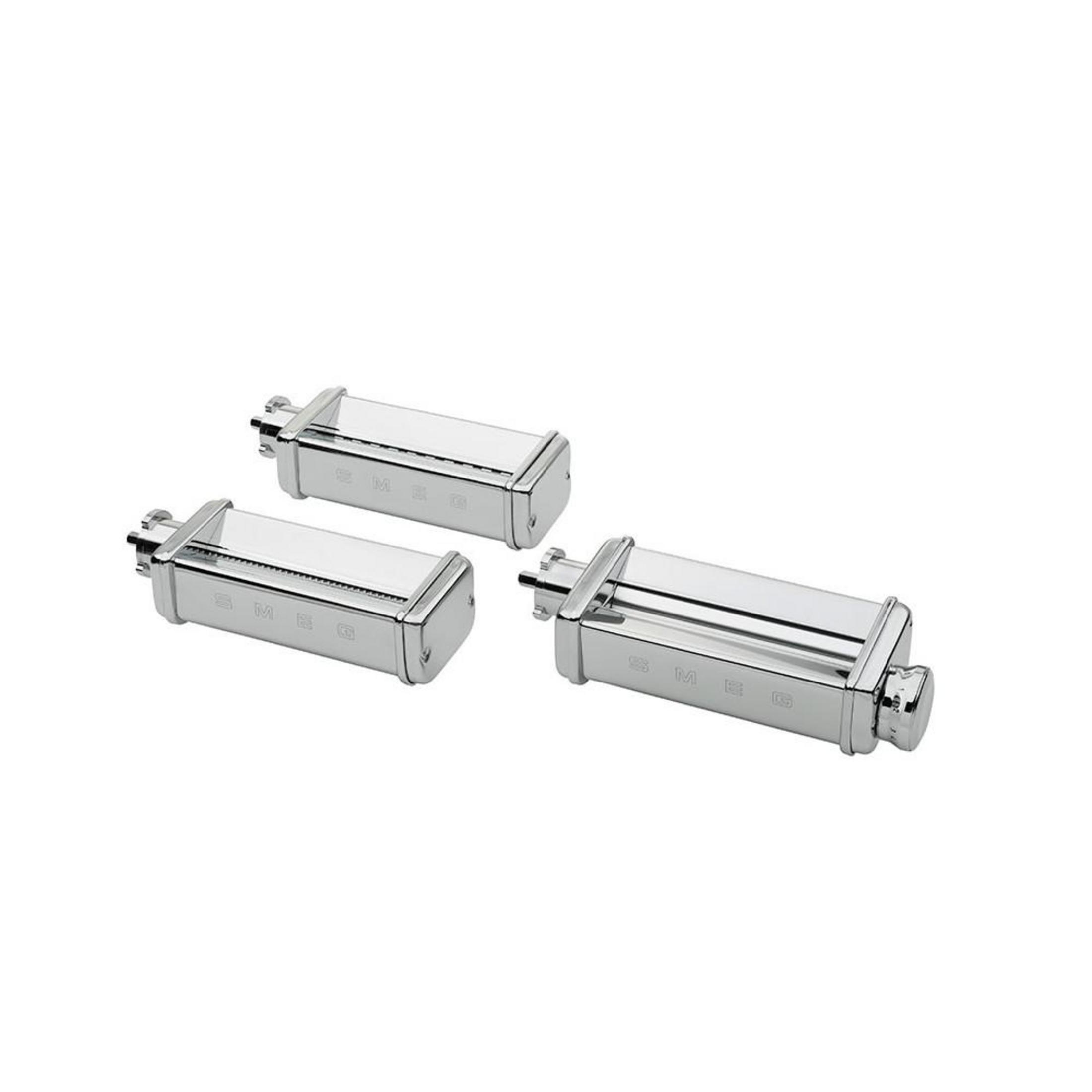 Tres accesorios plateados para máquina de pasta Smeg sobre fondo blanco.